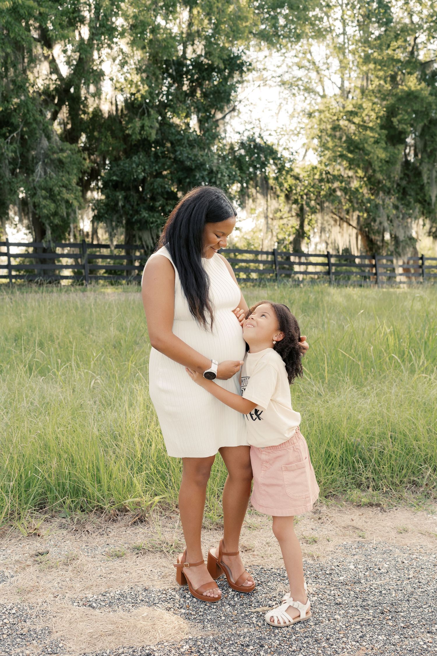A touching family moment captured on a gravel path with grass and trees in background.