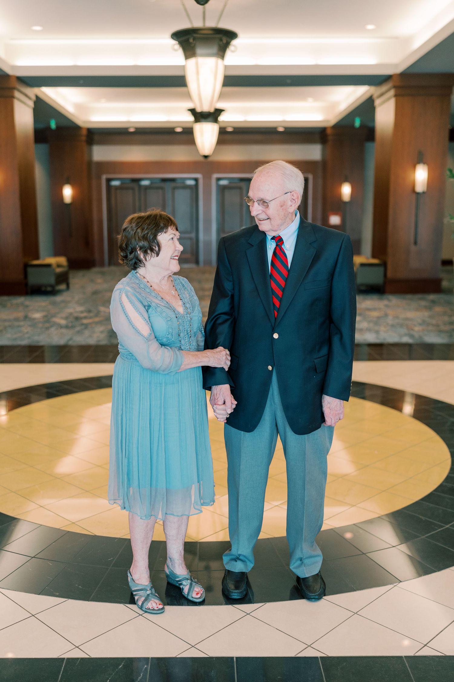 Couple walking together on decorative tile floor in elegant lobby setting.