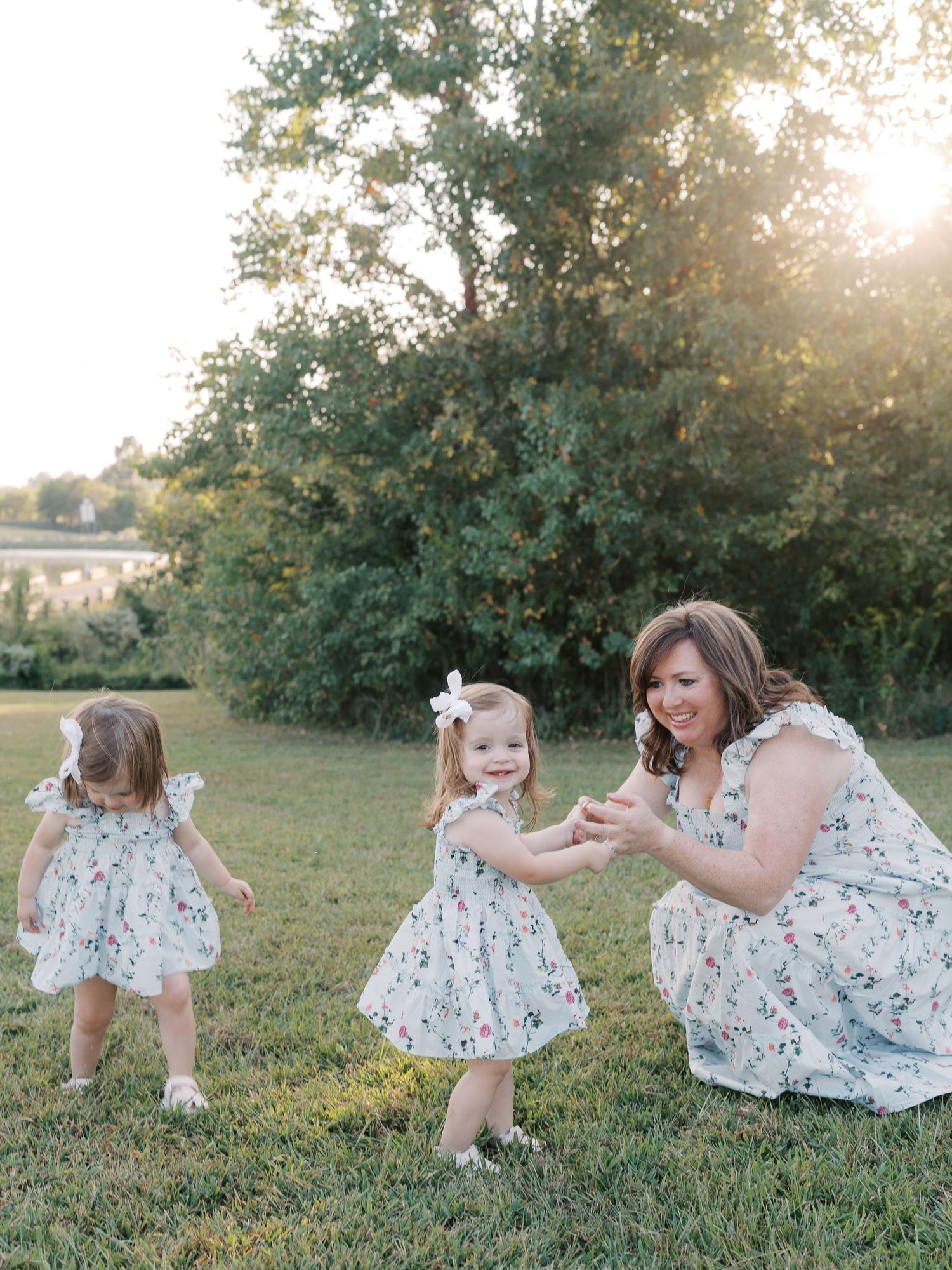 Child in summer dress playing and dancing in grassy field at sunset.