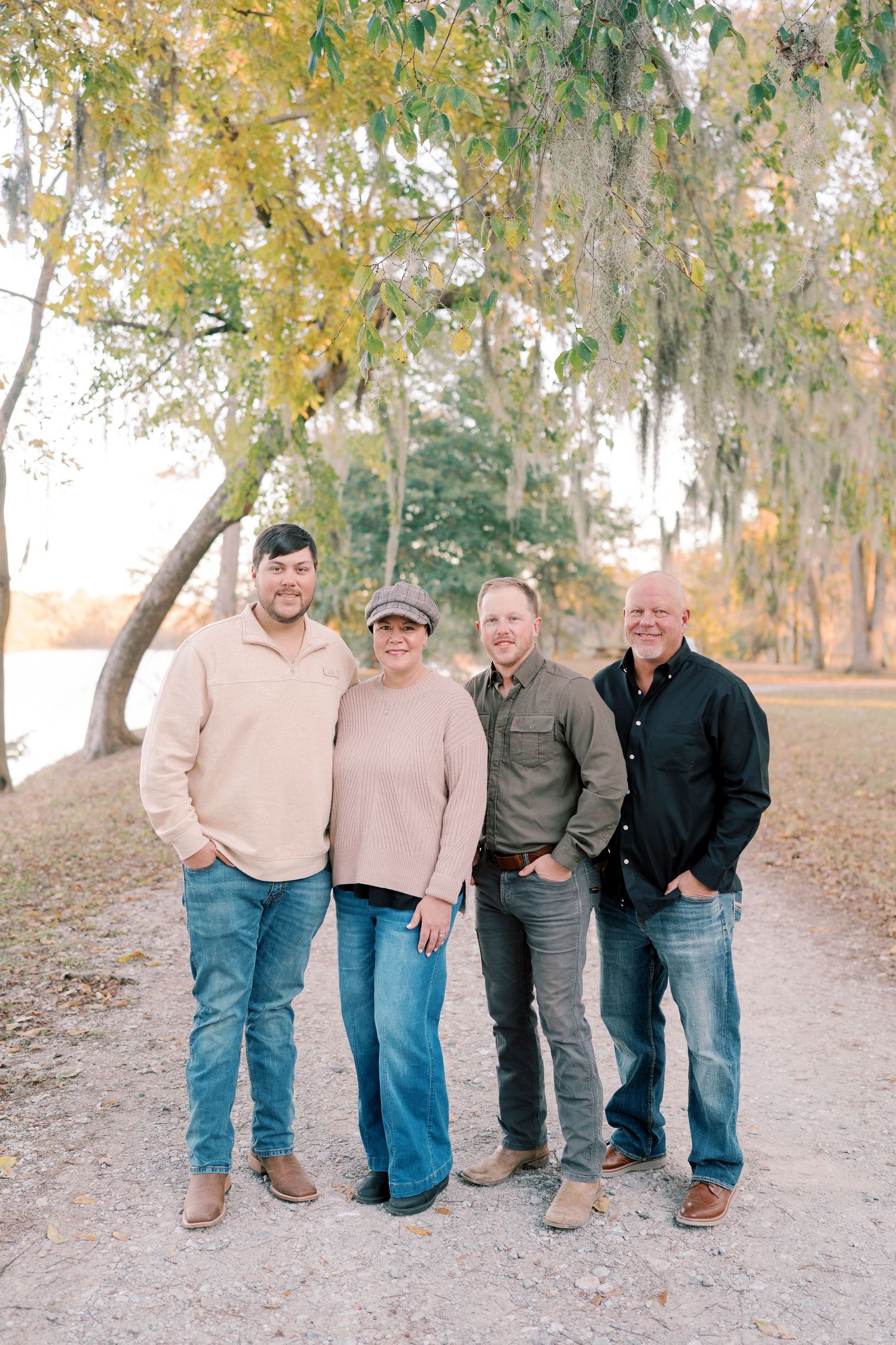 Four people stand together on a dirt path with autumn trees and Spanish moss in the background.