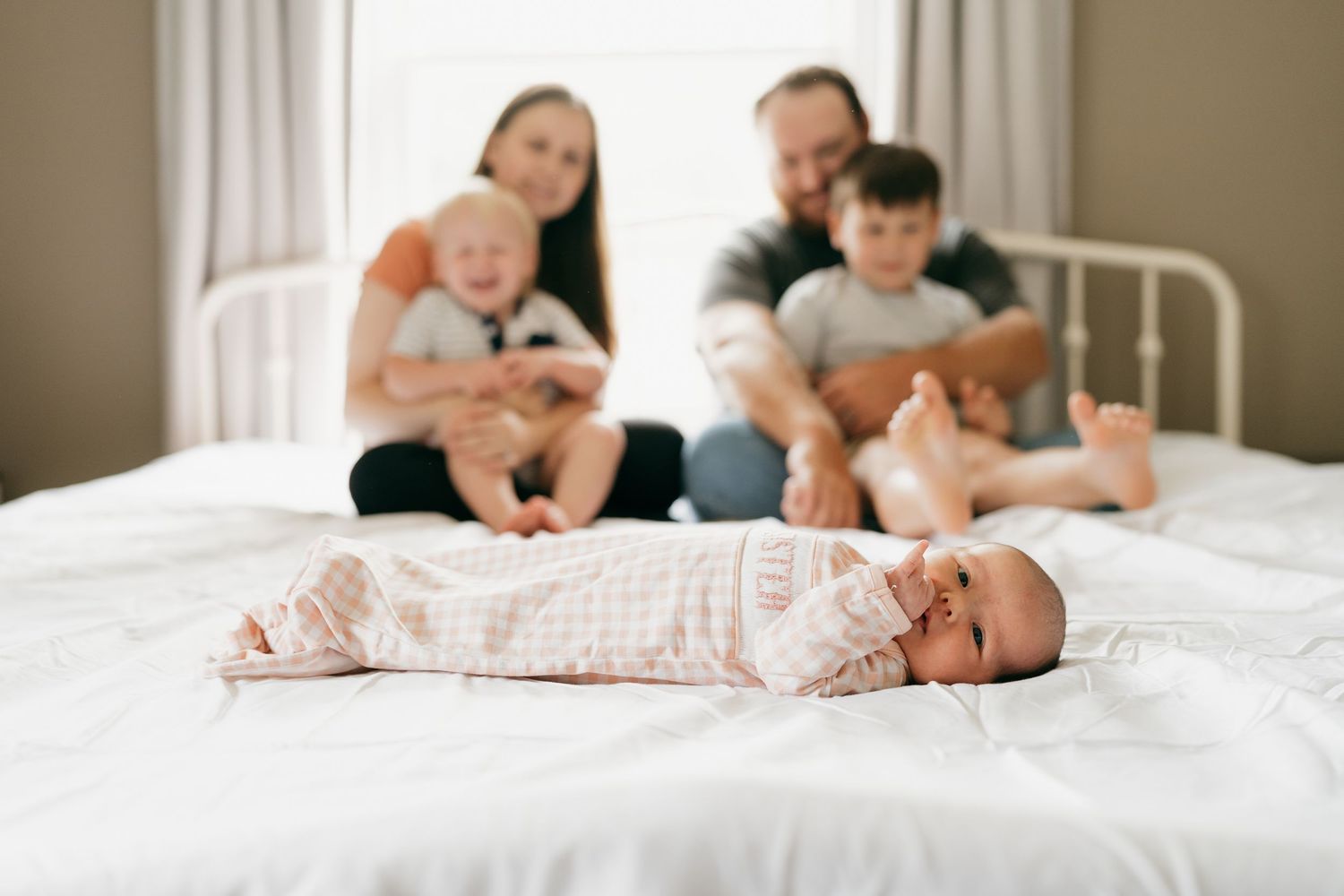 Lifestyle family photography session with white bedding and natural window light.
