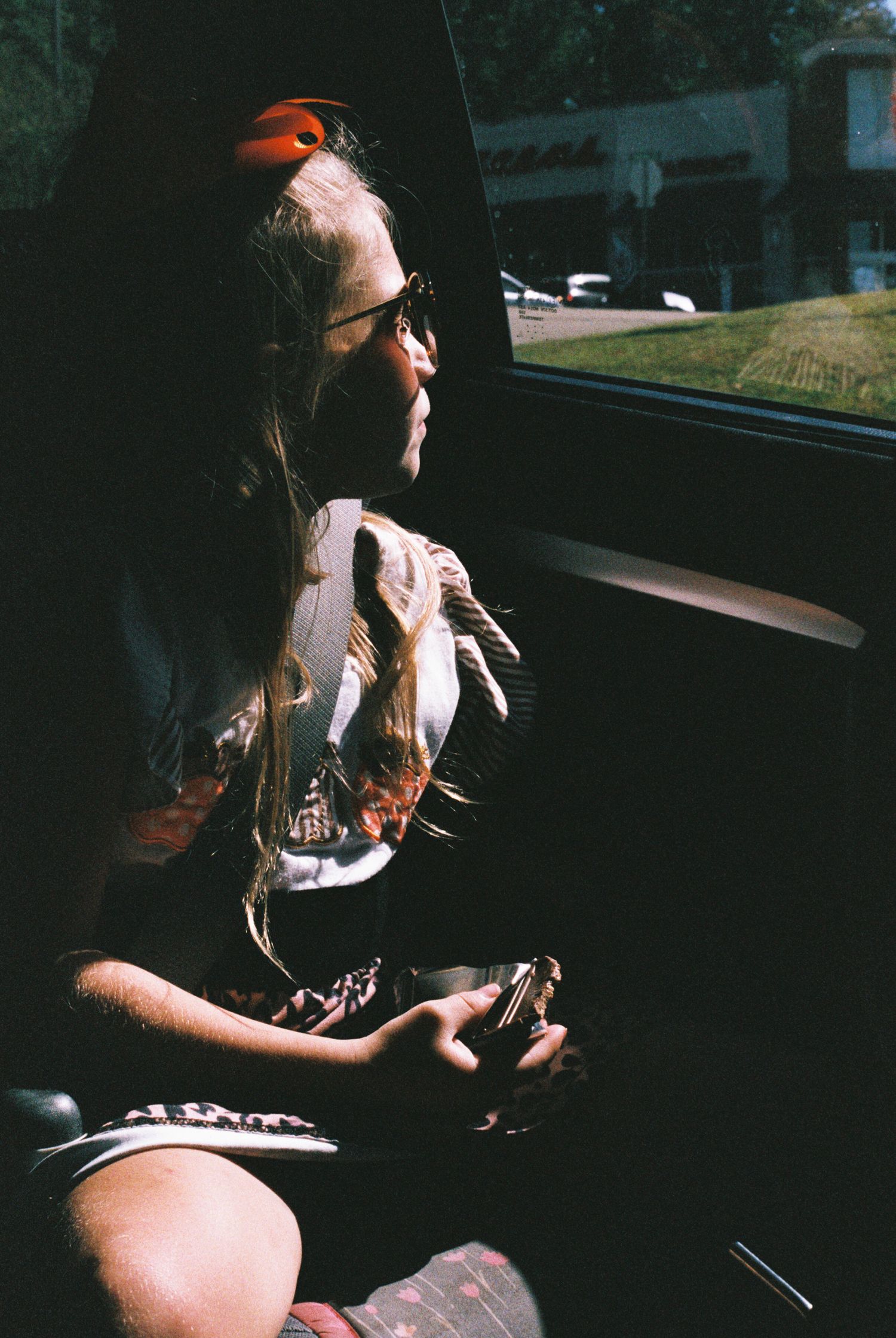 Person wearing a baseball cap sits in a dark car interior.