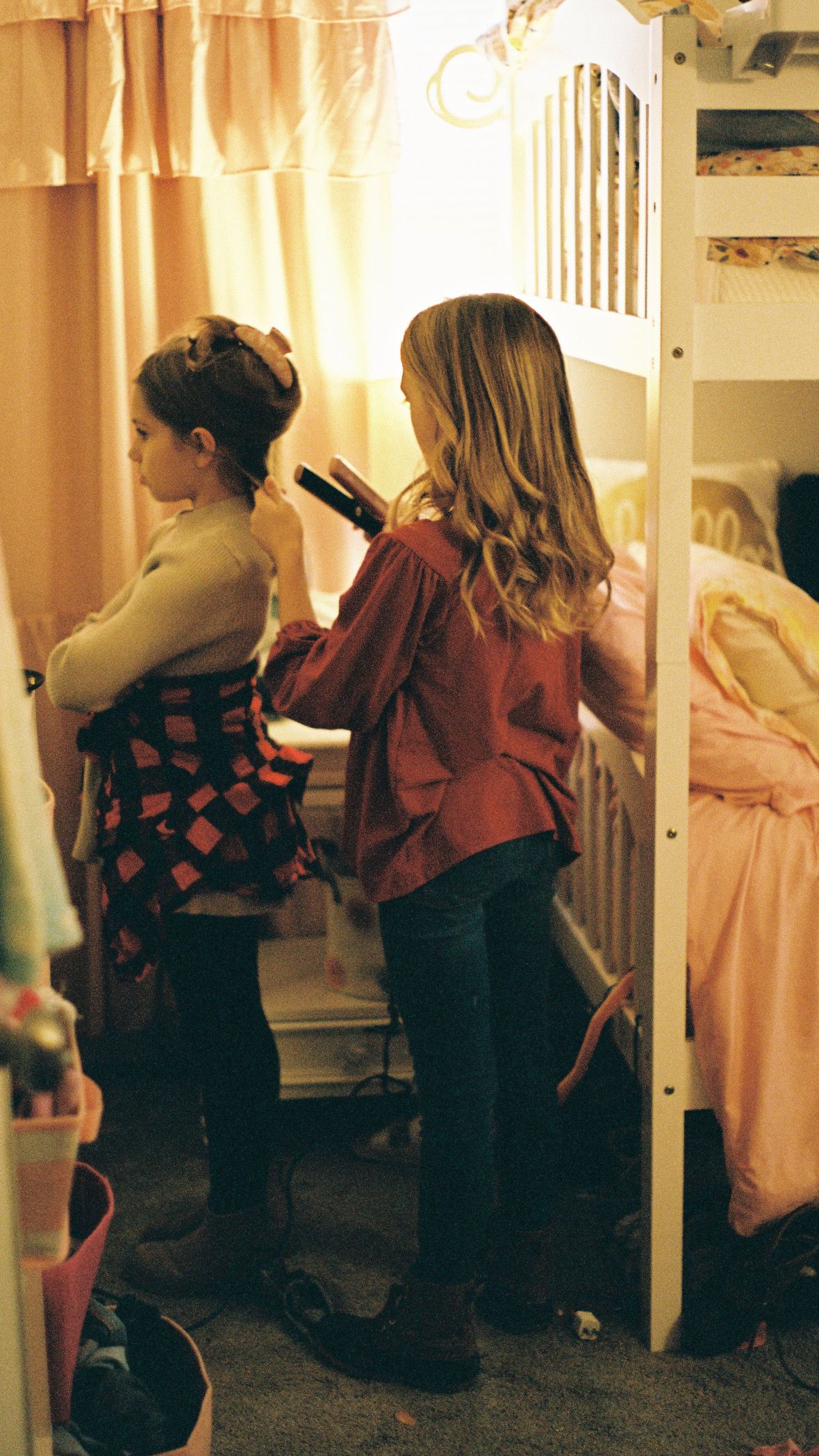 Two people getting ready in a dimly lit room with warm lighting and curtains.