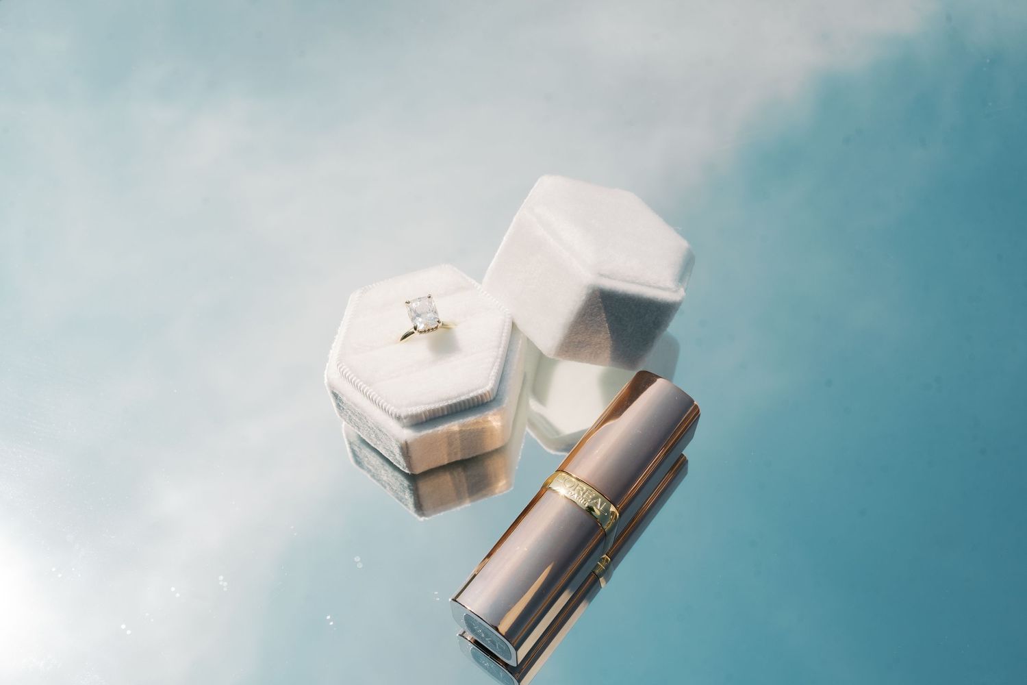 Wedding accessories and jewelry boxes arranged against soft blue sky background.