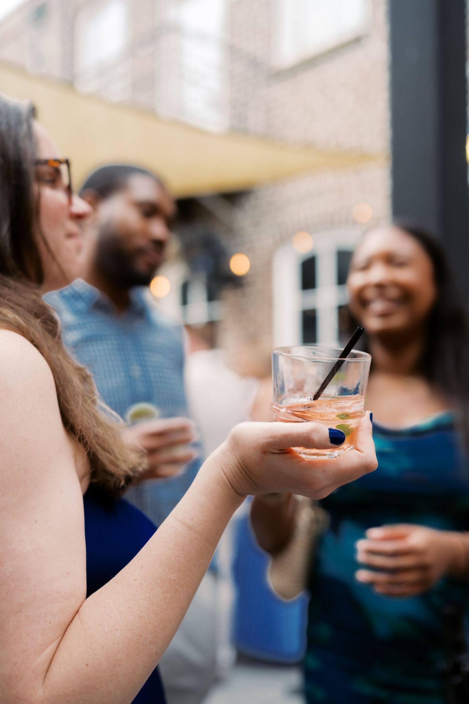 Close-up shots of hands holding cocktail glasses at a social gathering.