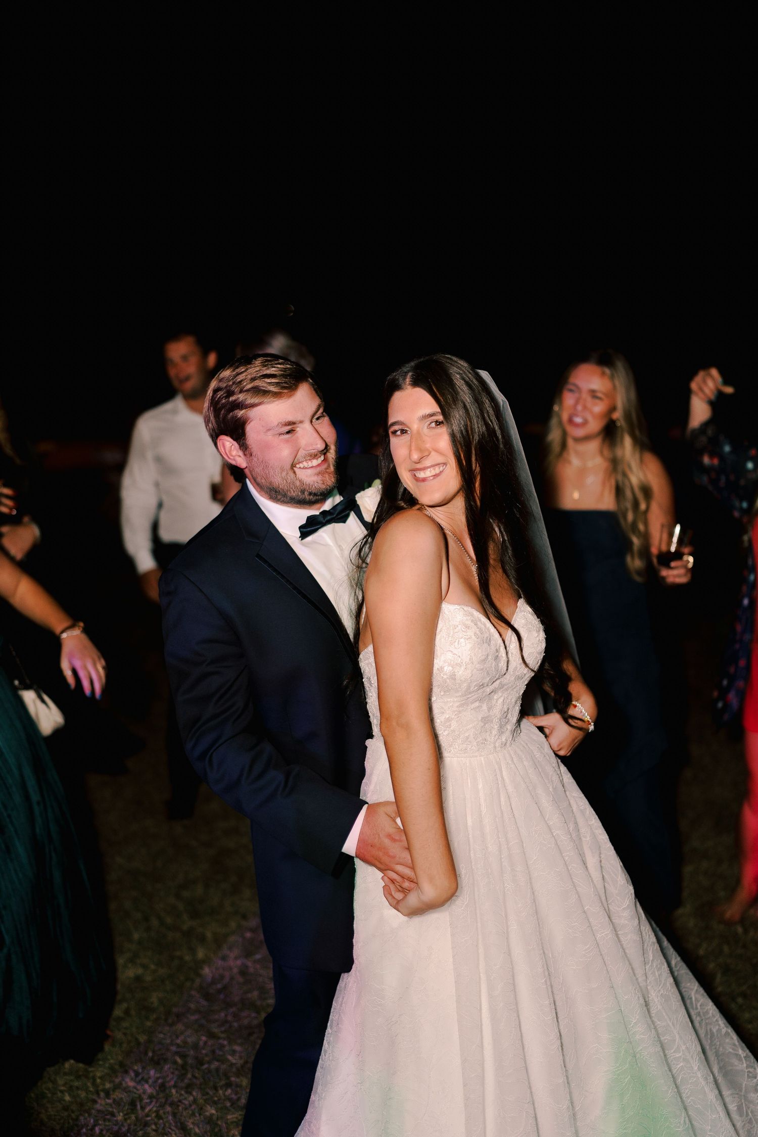Joyful dancing and celebration at a nighttime wedding reception.