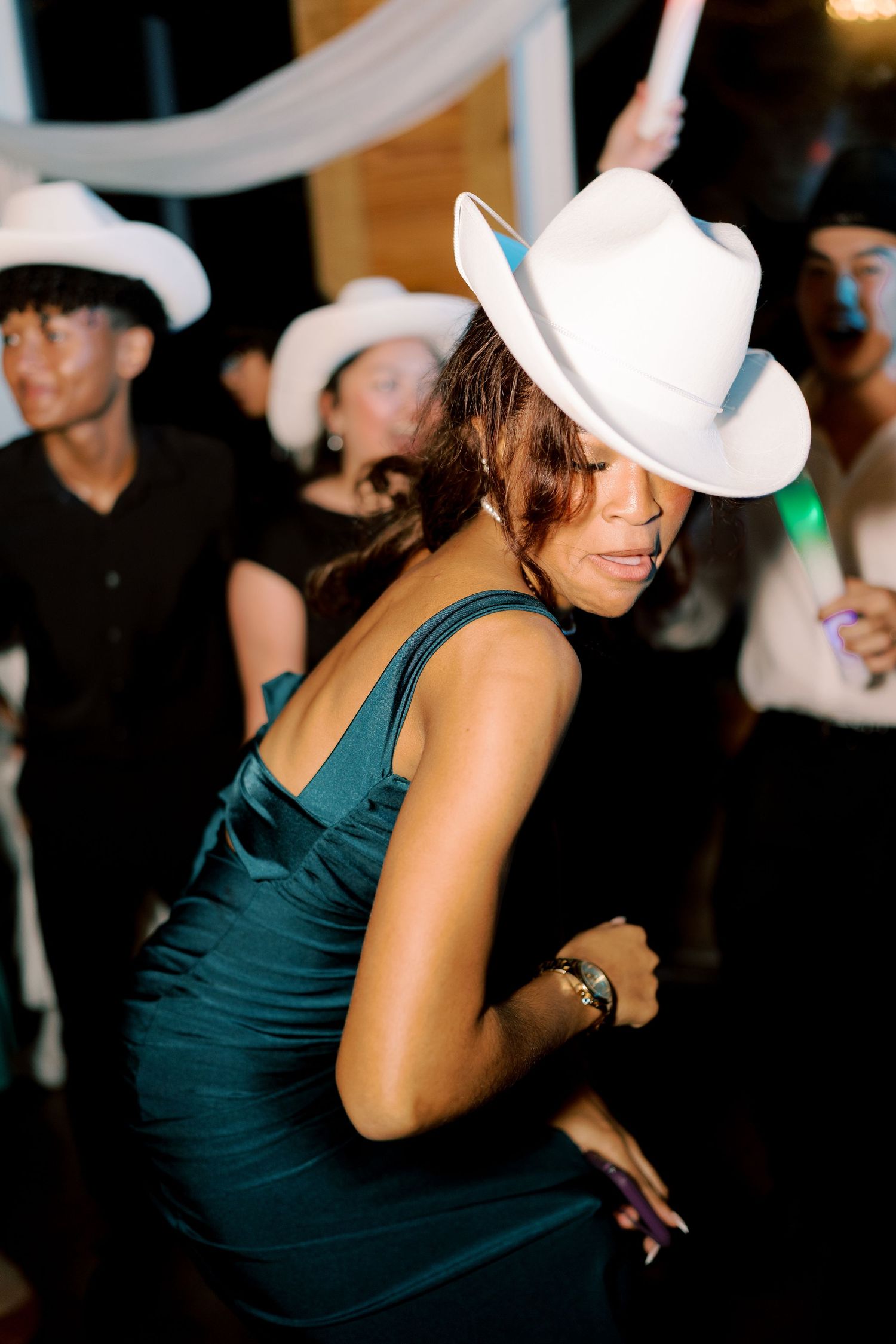 Dancers wearing white cowboy hats and dark outfits moving to the music.