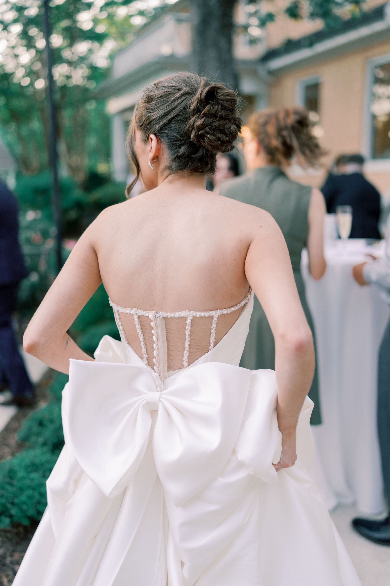 Detail of a wedding dress back featuring delicate buttons and a large decorative bow.