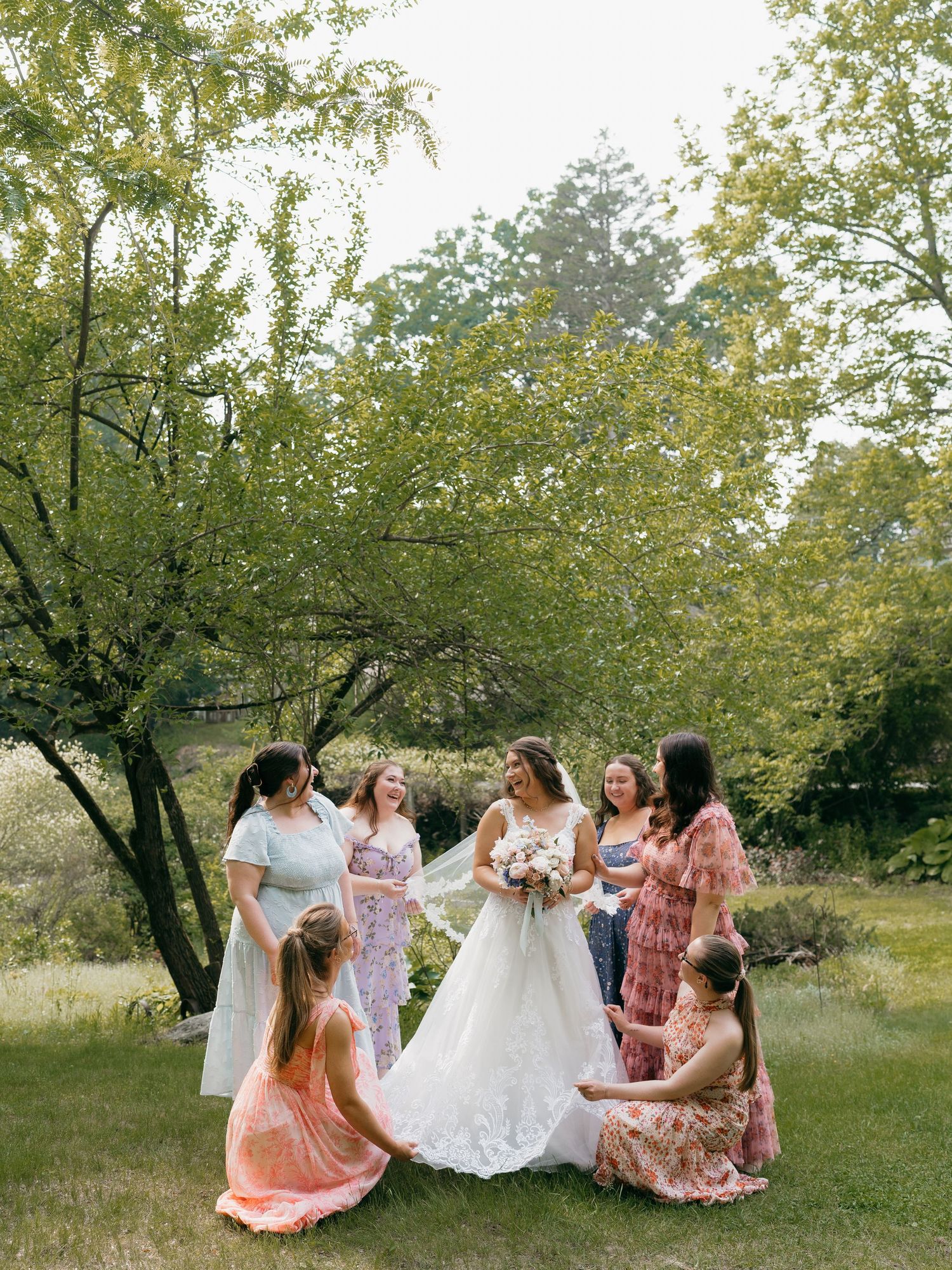 Group photo session in a lush garden with flowing dresses and natural scenery.