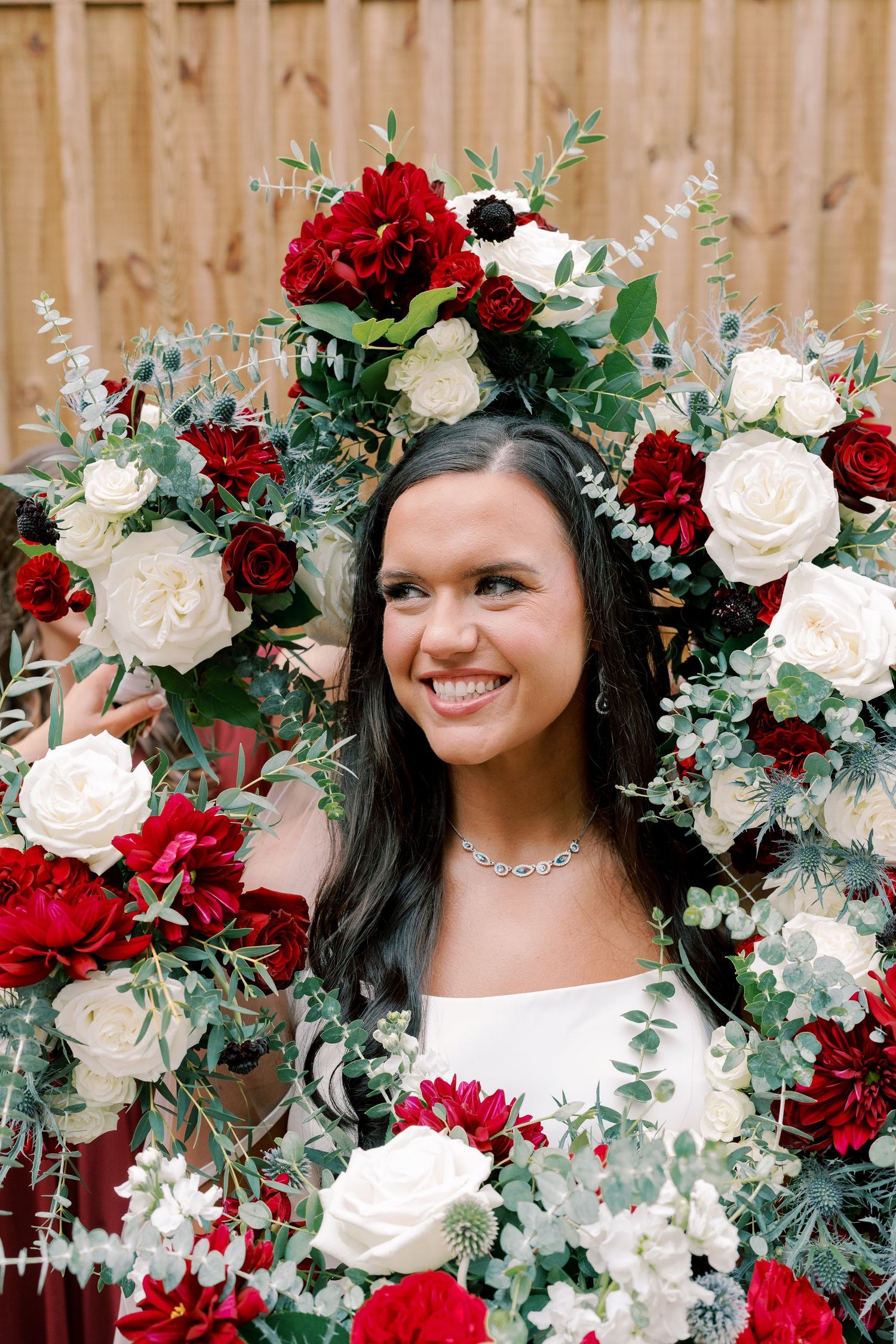 Beautiful floral crown with red and white roses adorns elegant bridal portrait.