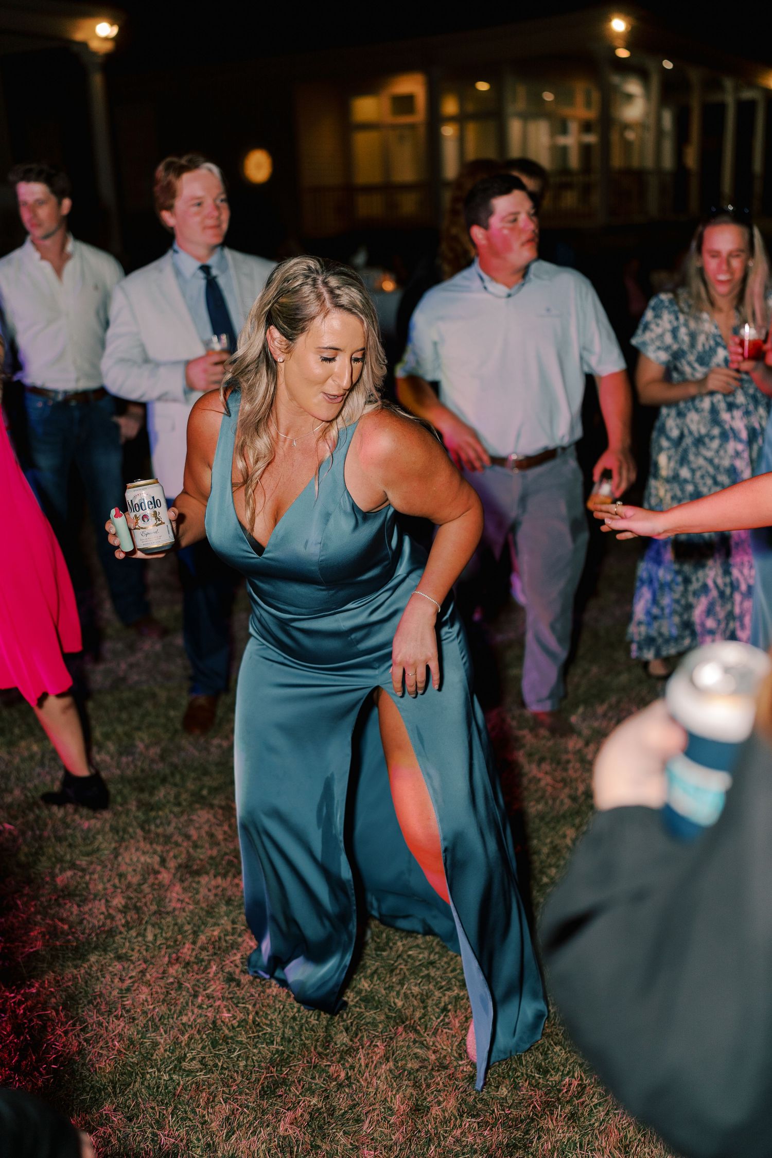 Wedding guests in formal attire dancing enthusiastically at an outdoor reception.