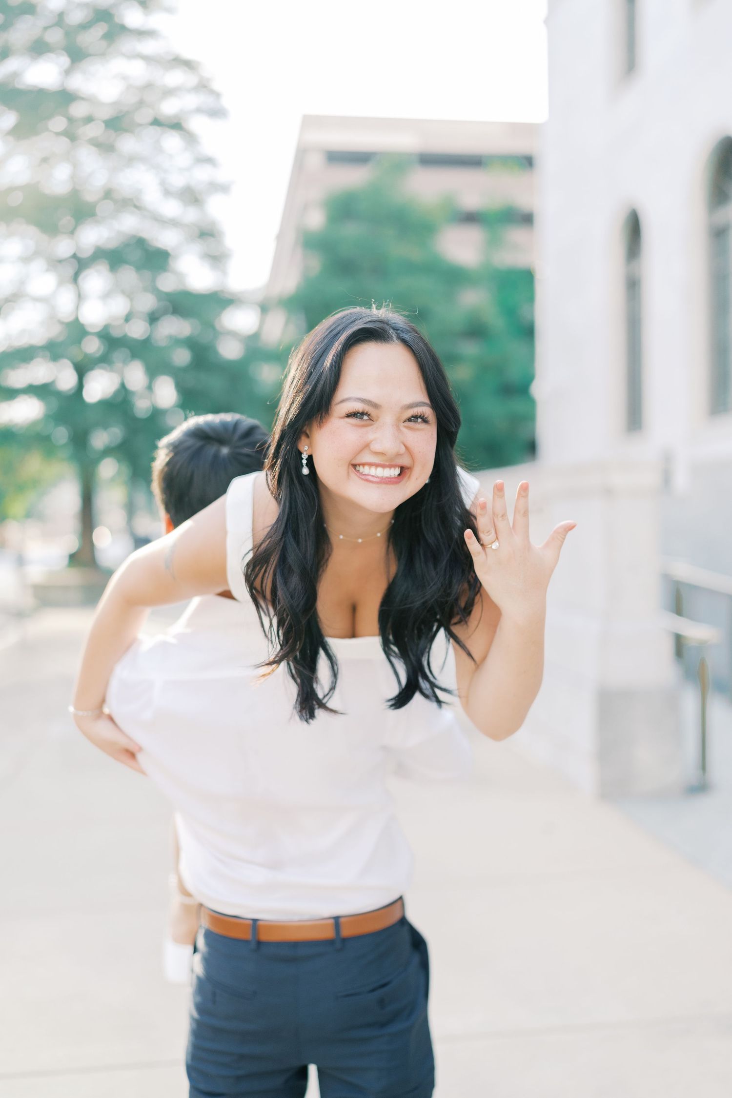 Joyful outdoor portraits showing animated expressions against a white architectural backdrop.