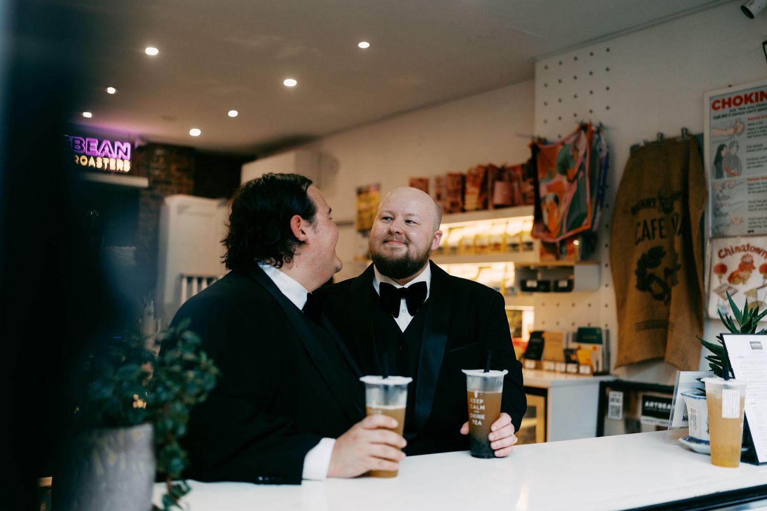 Two people in formal attire having drinks at a bar counter.