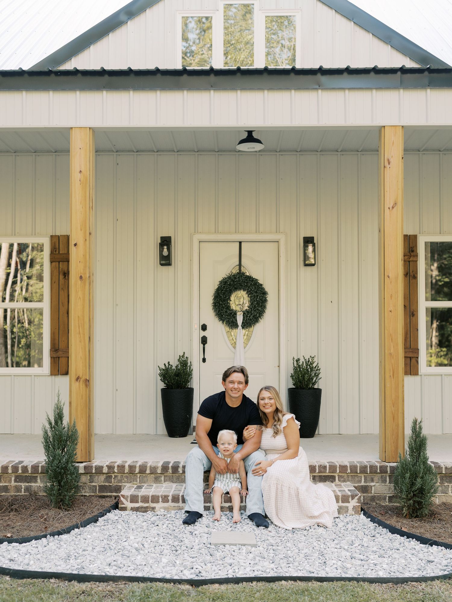 Wide view of modern farmhouse exterior with white siding and decorative posts.