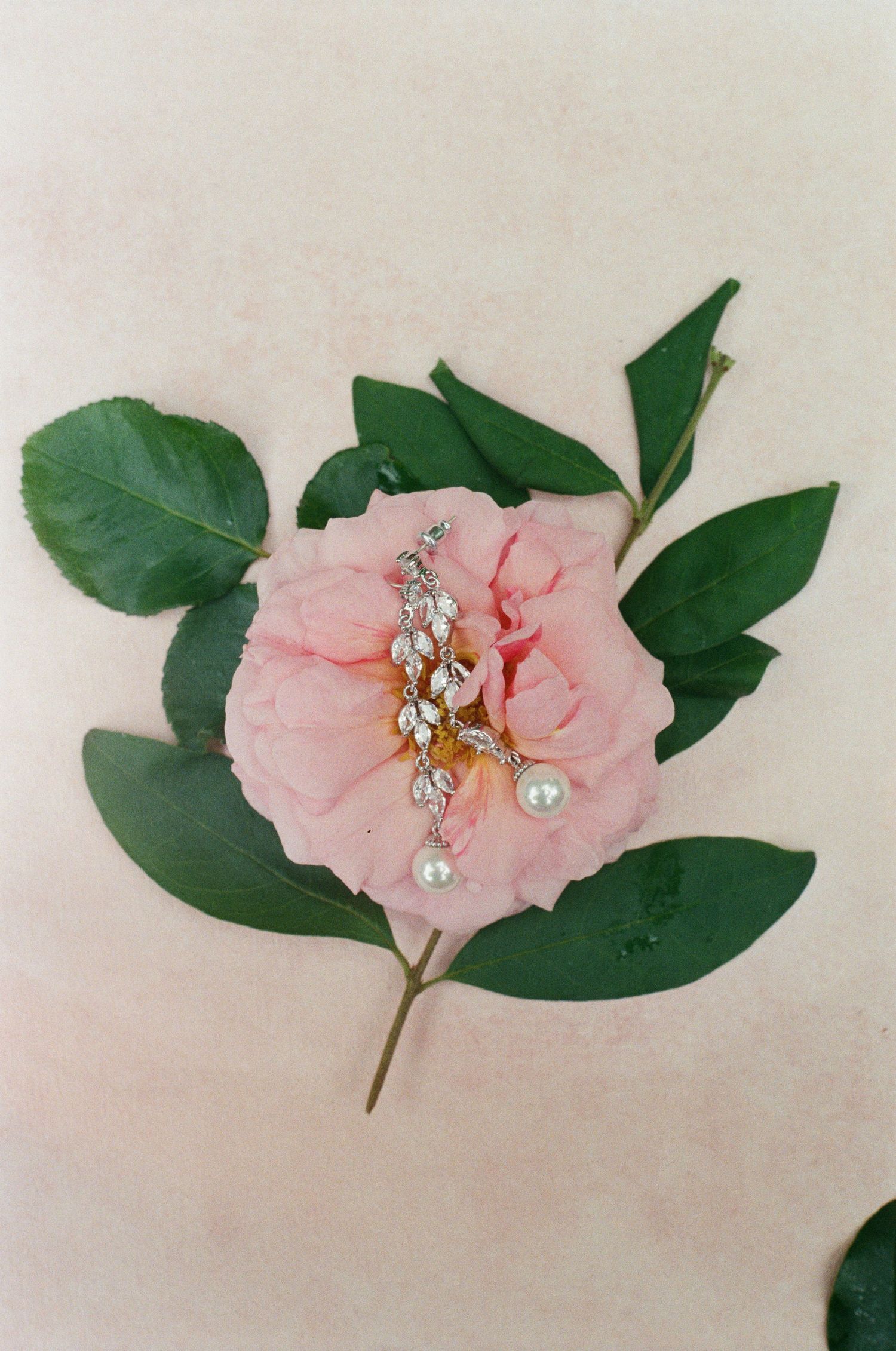 Pink floral hair accessory with pearls and crystals on light background.
