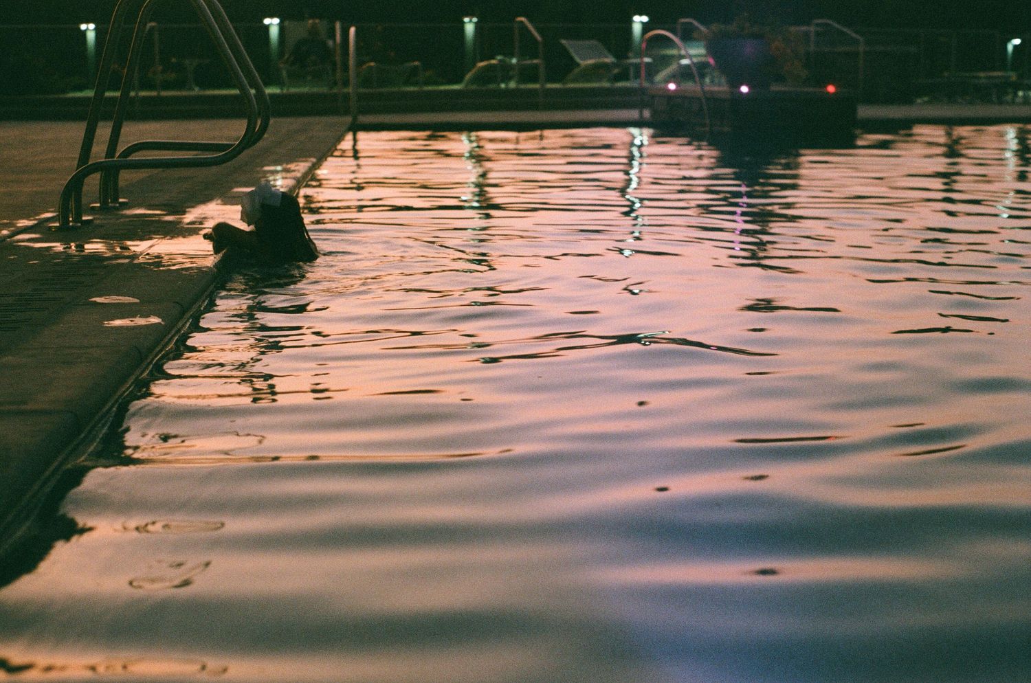 Calm water surface reflecting pink sunset colors and dock lights.