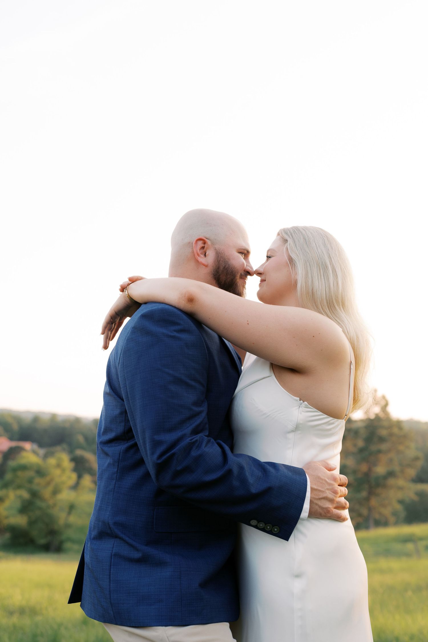 Couple embracing in intimate moment against natural outdoor backdrop.