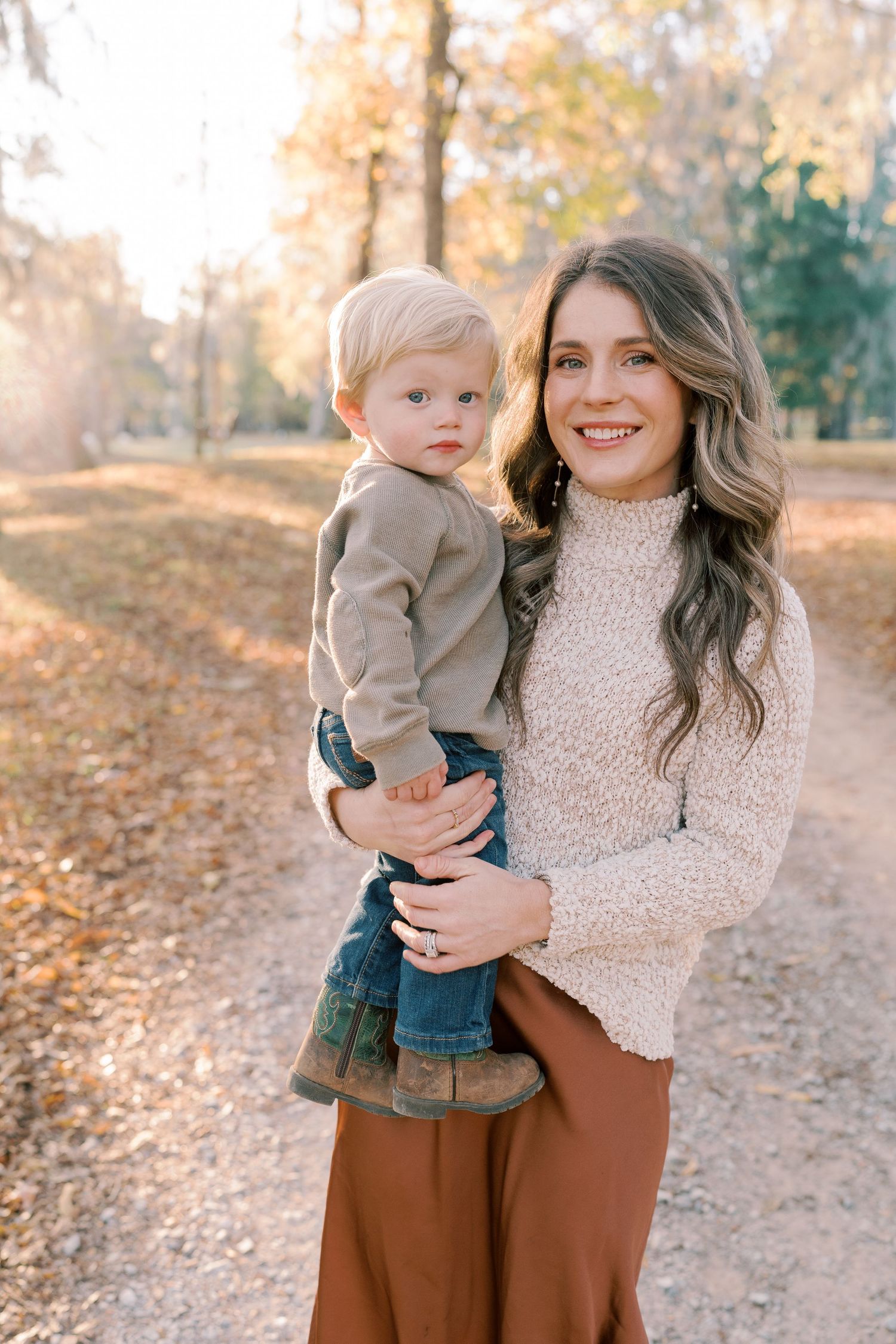 Portrait in autumn setting with cream sweater and rust-colored skirt.