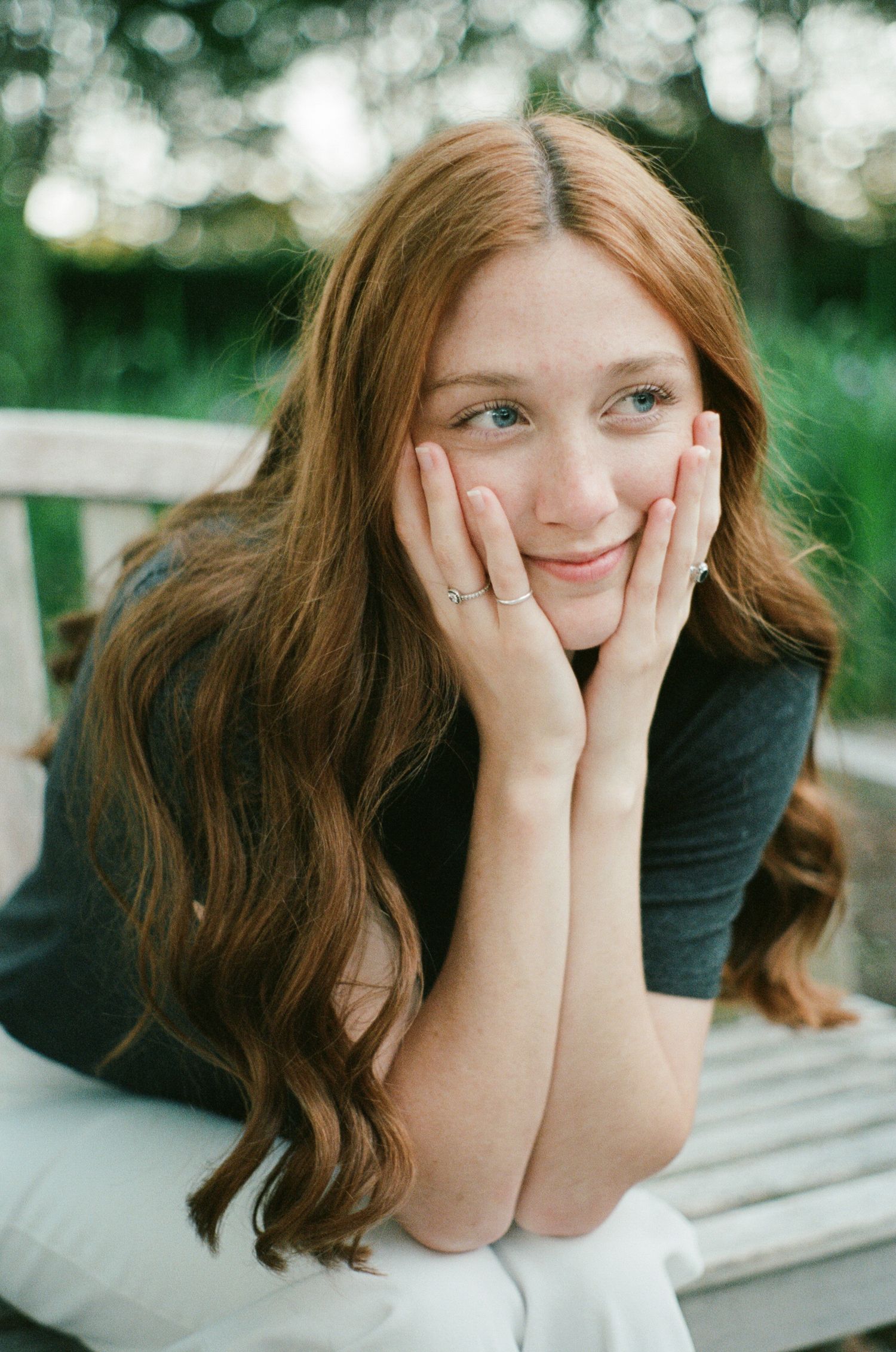 Portrait series showing relaxed poses with hands framing face against natural background.