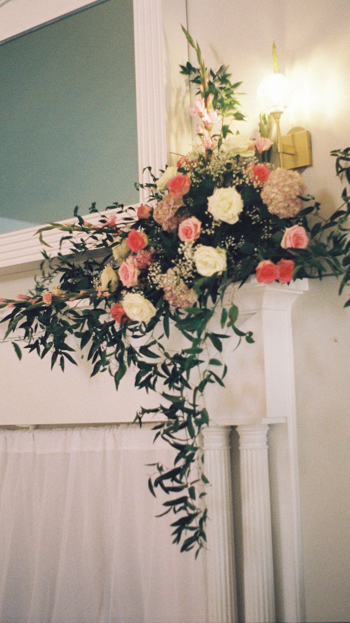 Elegant floral arrangement with pink and white roses decorating a white column indoors.