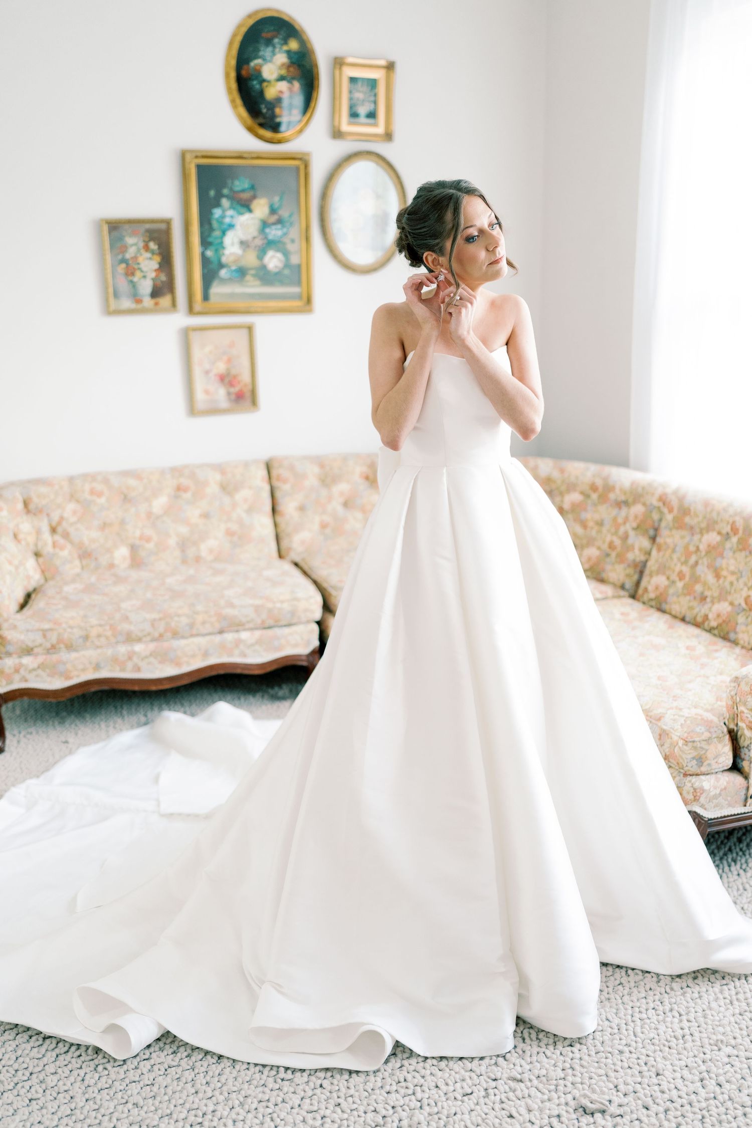 Elegant white wedding gown with a flowing train displayed in a room with vintage decor.