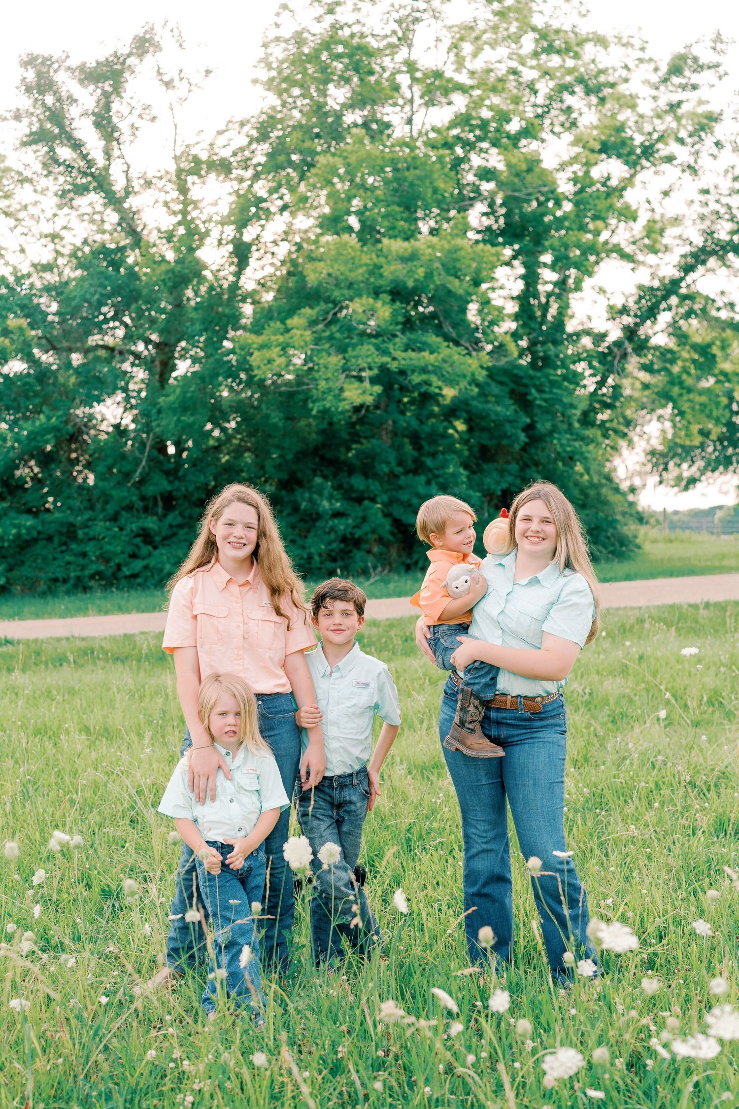 Family group poses together in a wildflower meadow on a sunny day.