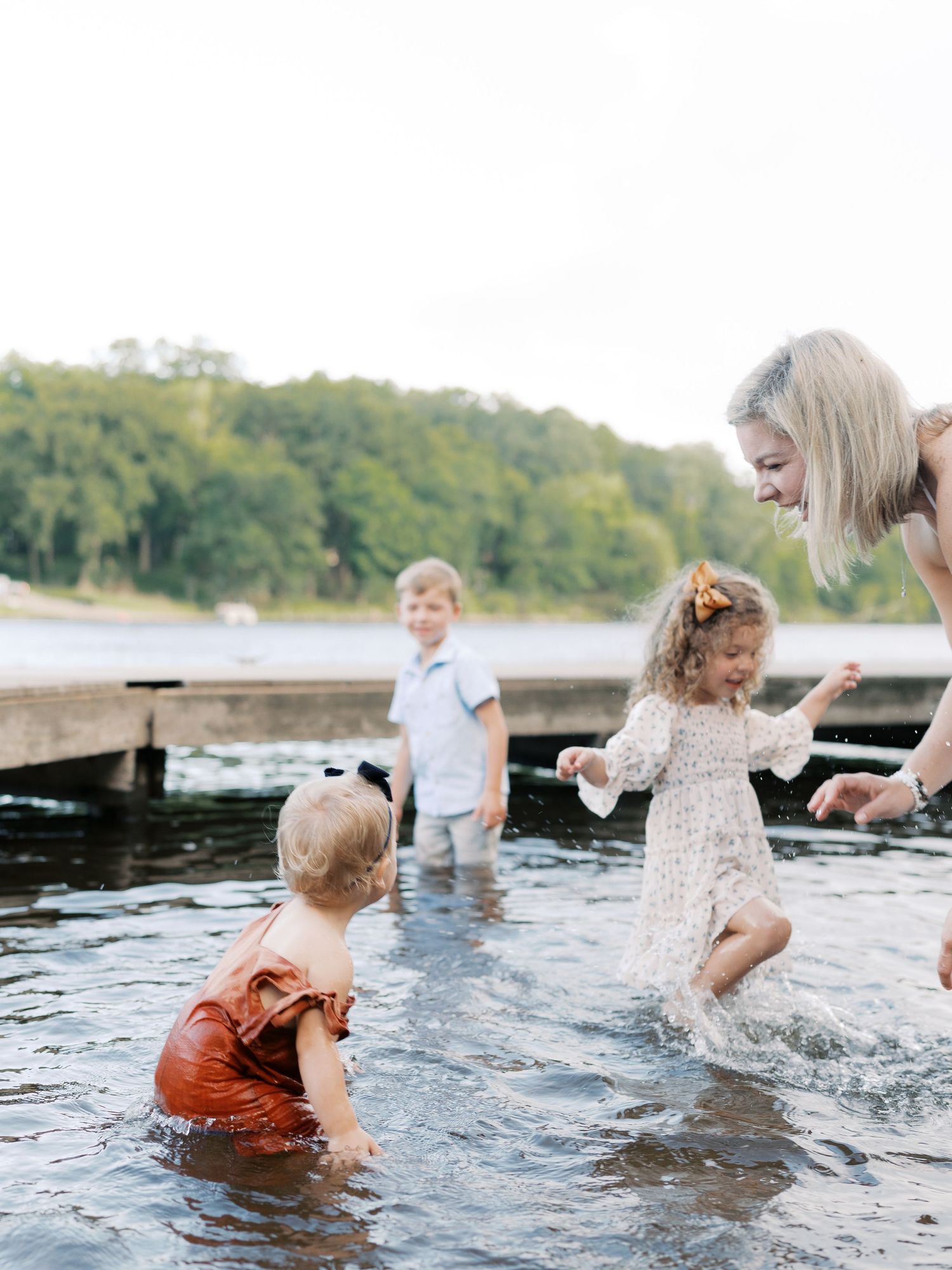 Family members splashing and playing together in shallow water during sunset.