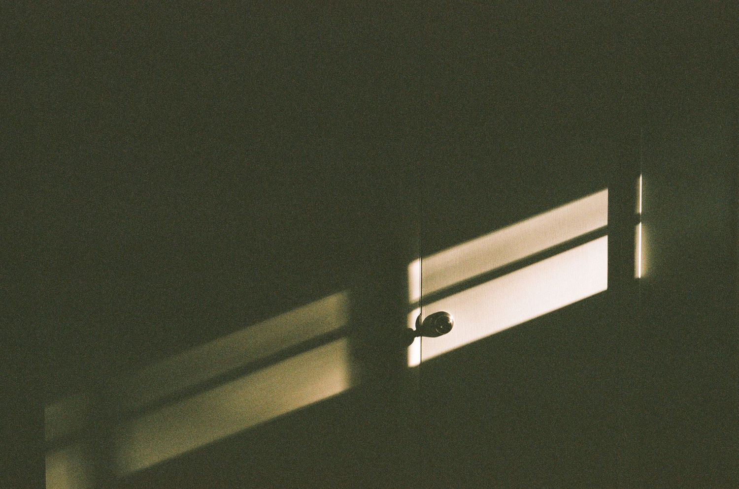 Dramatic window light creates elongated shadows on a dark interior wall.