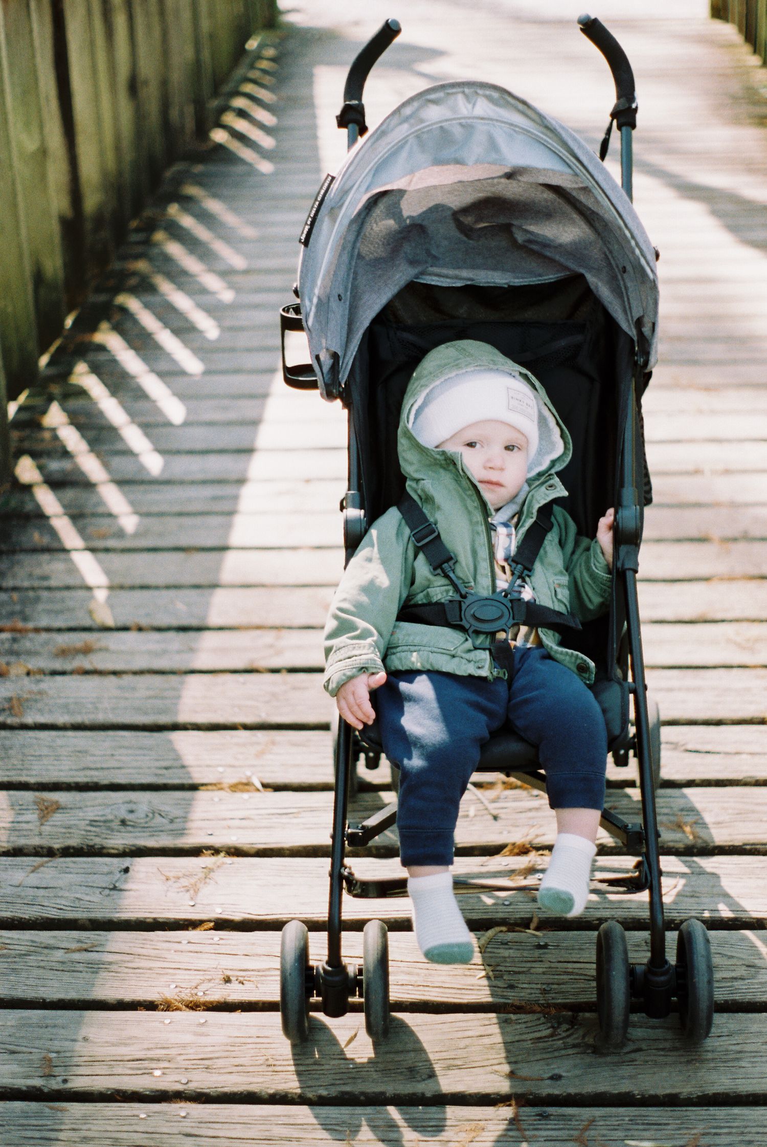 Stroller on a wooden boardwalk surrounded by green fencing.