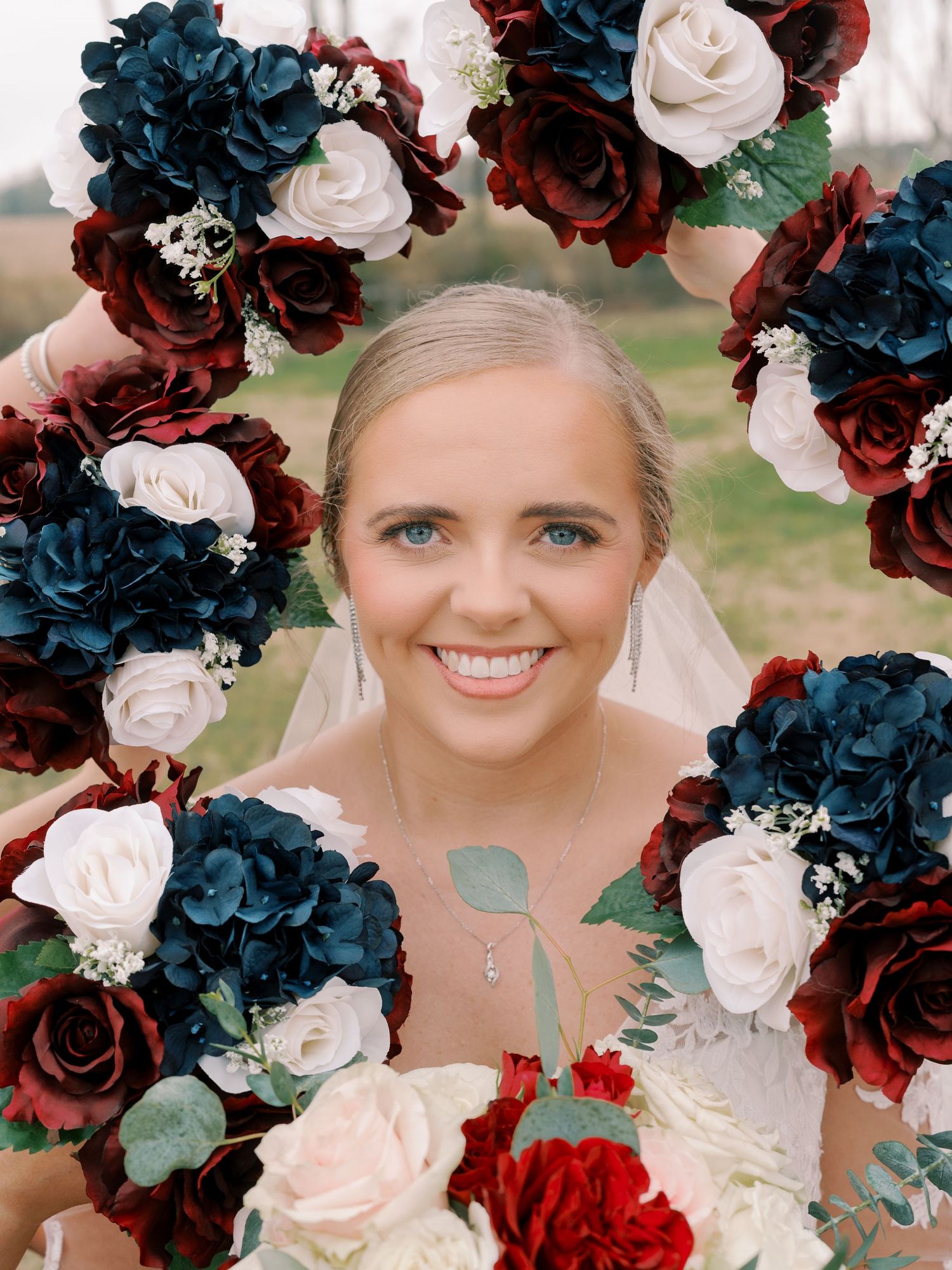 Wedding bouquet features deep navy, burgundy, and blush roses with eucalyptus accents.
