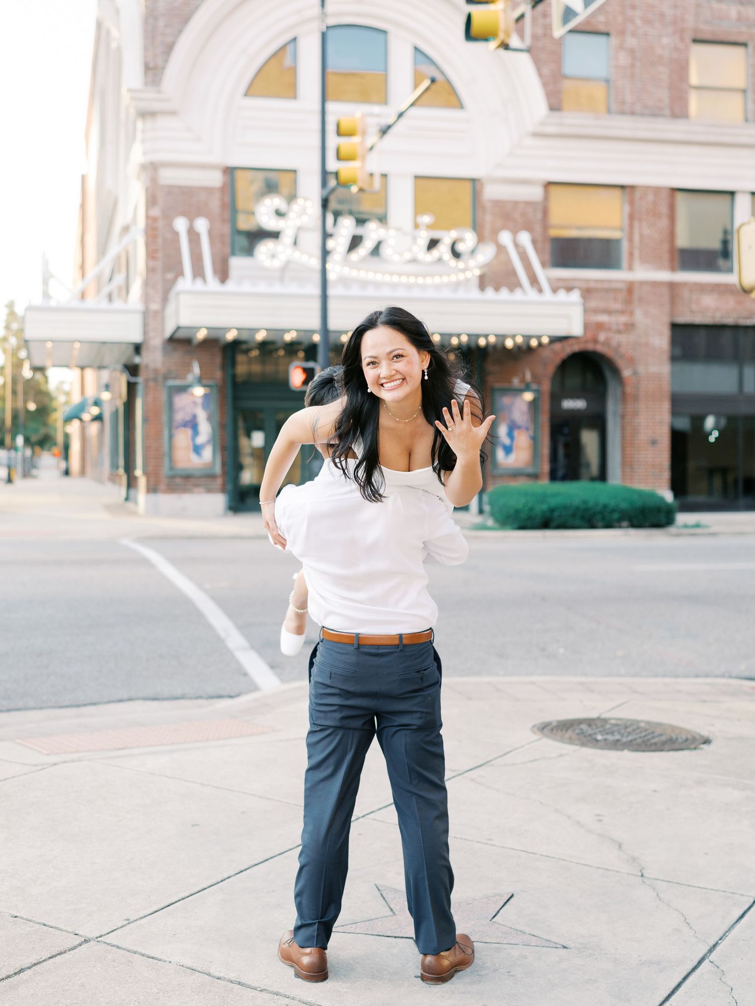 A couple dances playfully together on an urban street corner during a photoshoot.