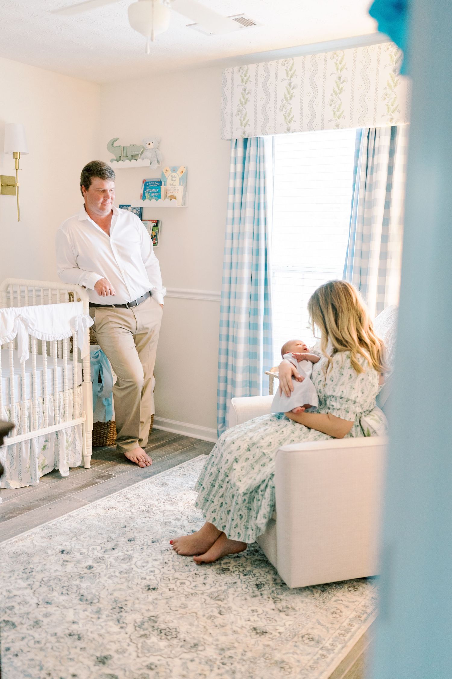 Parents-to-be share tender moments in a white nursery with blue accents and plush carpet.