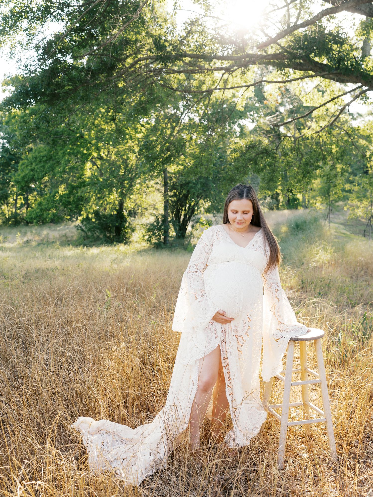 White lace dress catches sunlight in a golden field during sunset.