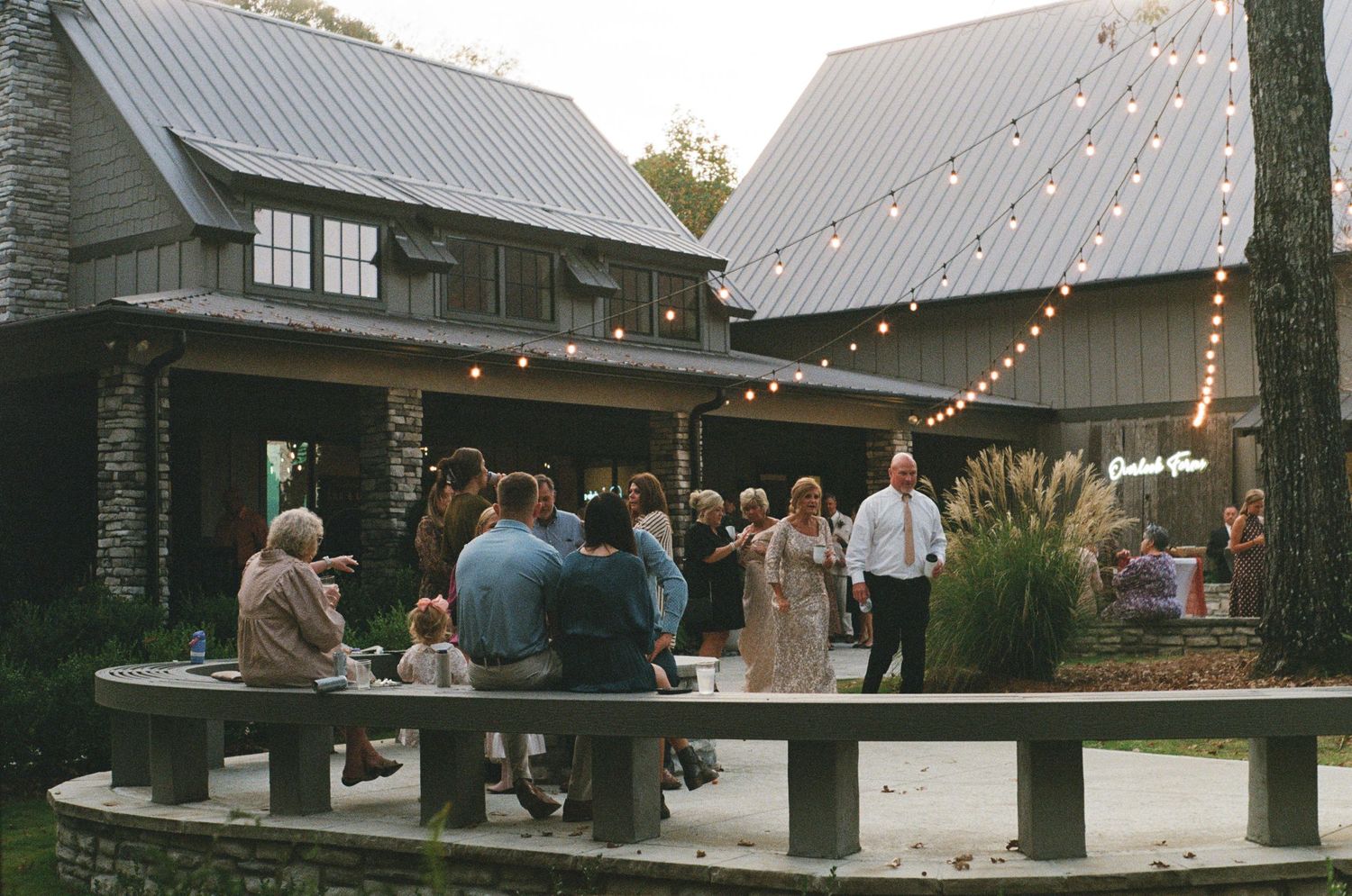 Rustic wooden pavilion venue decorated with string lights for an evening wedding reception.