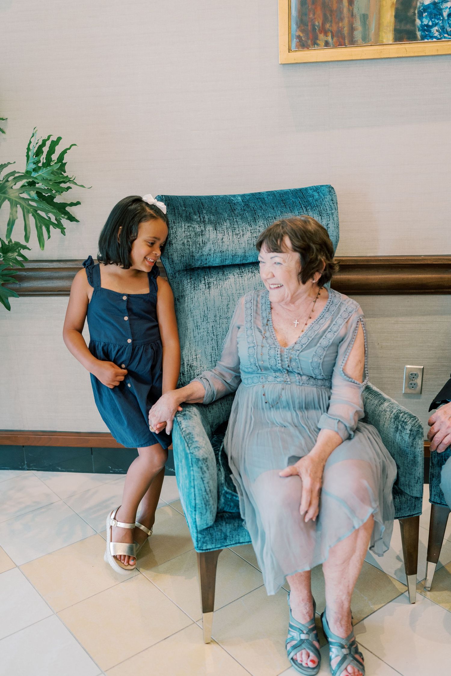 Two people having conversation while sitting on blue couch in lobby area.