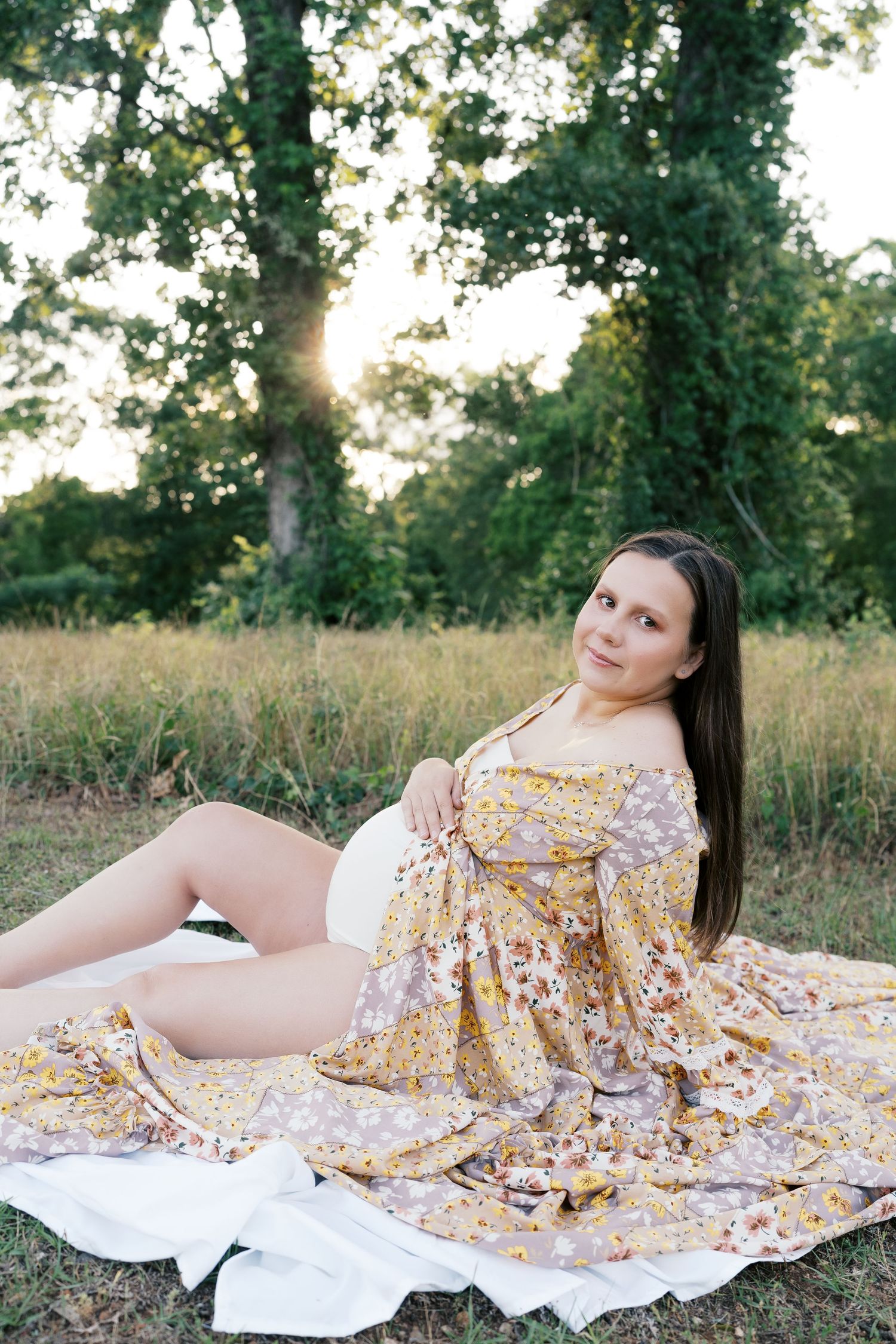 Dreamy maternity portraits with yellow floral dress against natural outdoor backdrop at sunset.
