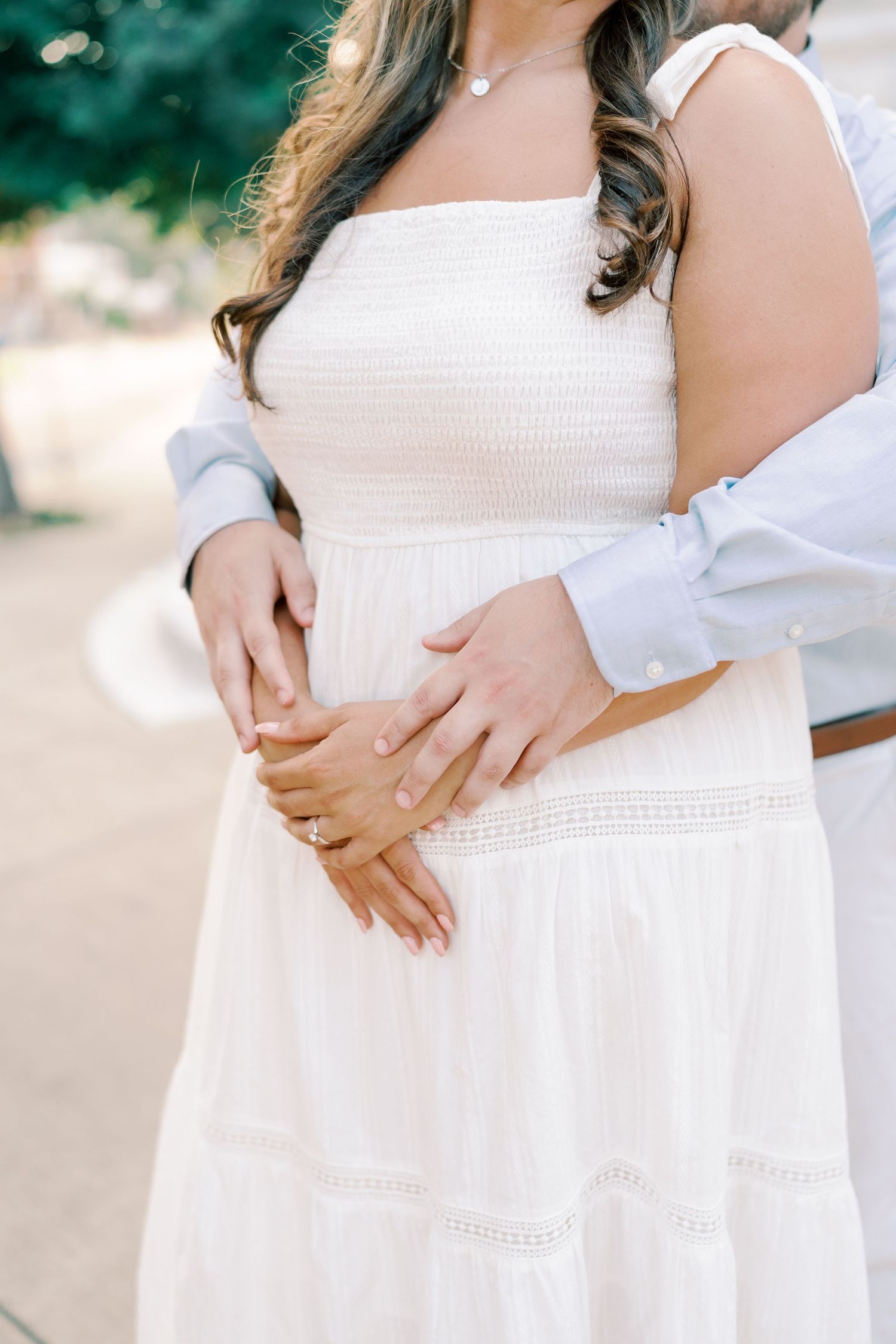 Close-up details of a white dress and gentle embrace during an engagement photoshoot.