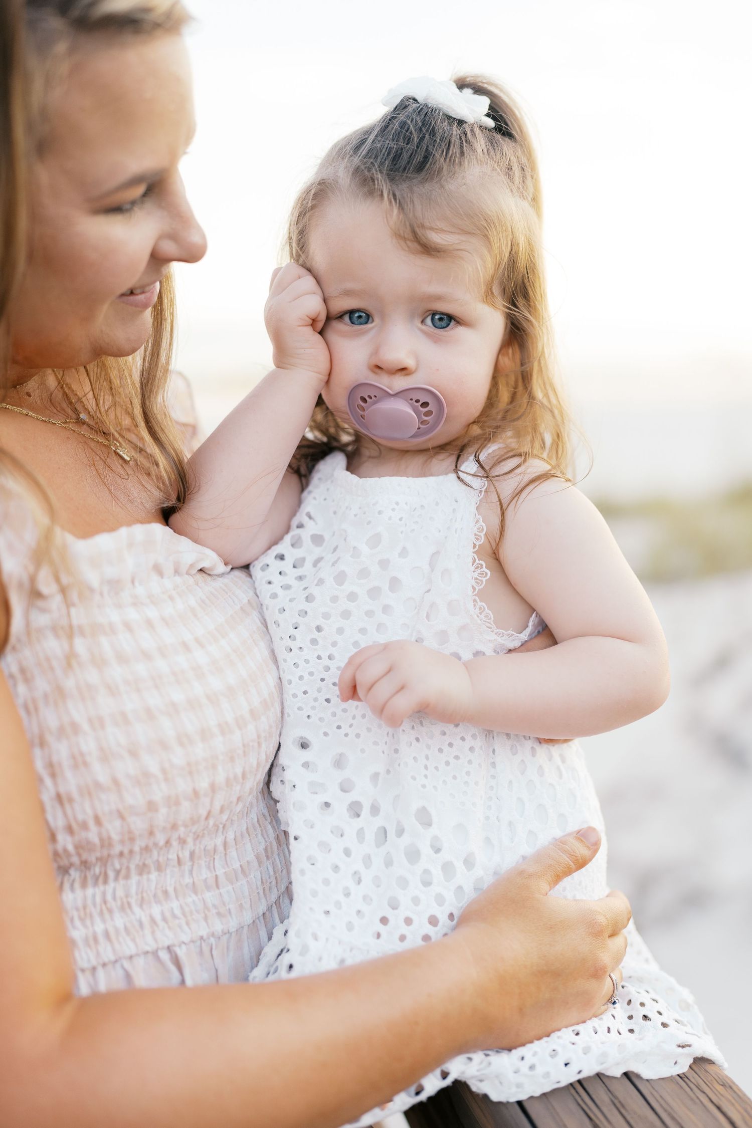Close-up shots of parent and child in white dresses sharing sweet moments together.