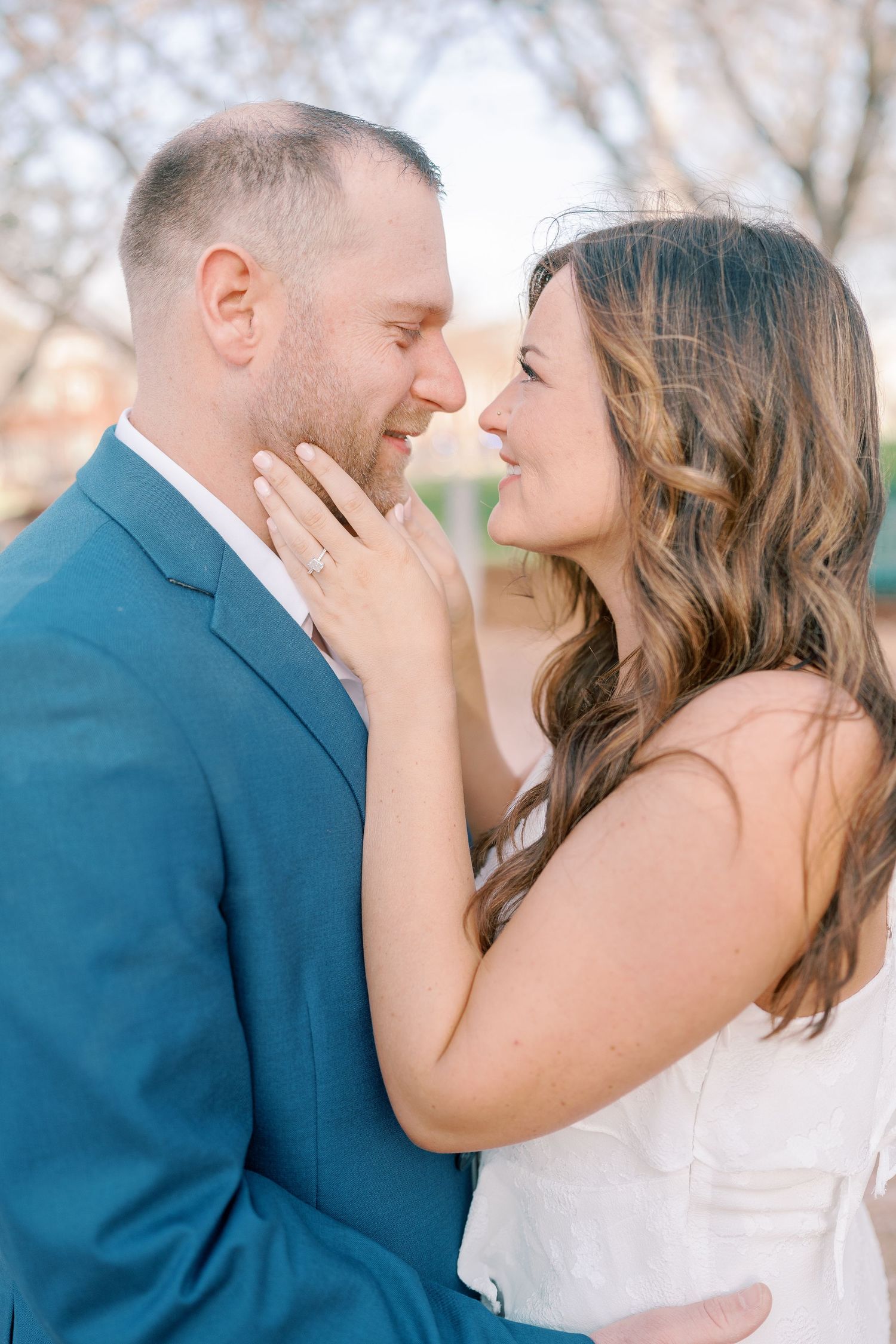 Intimate romantic moment captured outdoors under blooming spring trees.