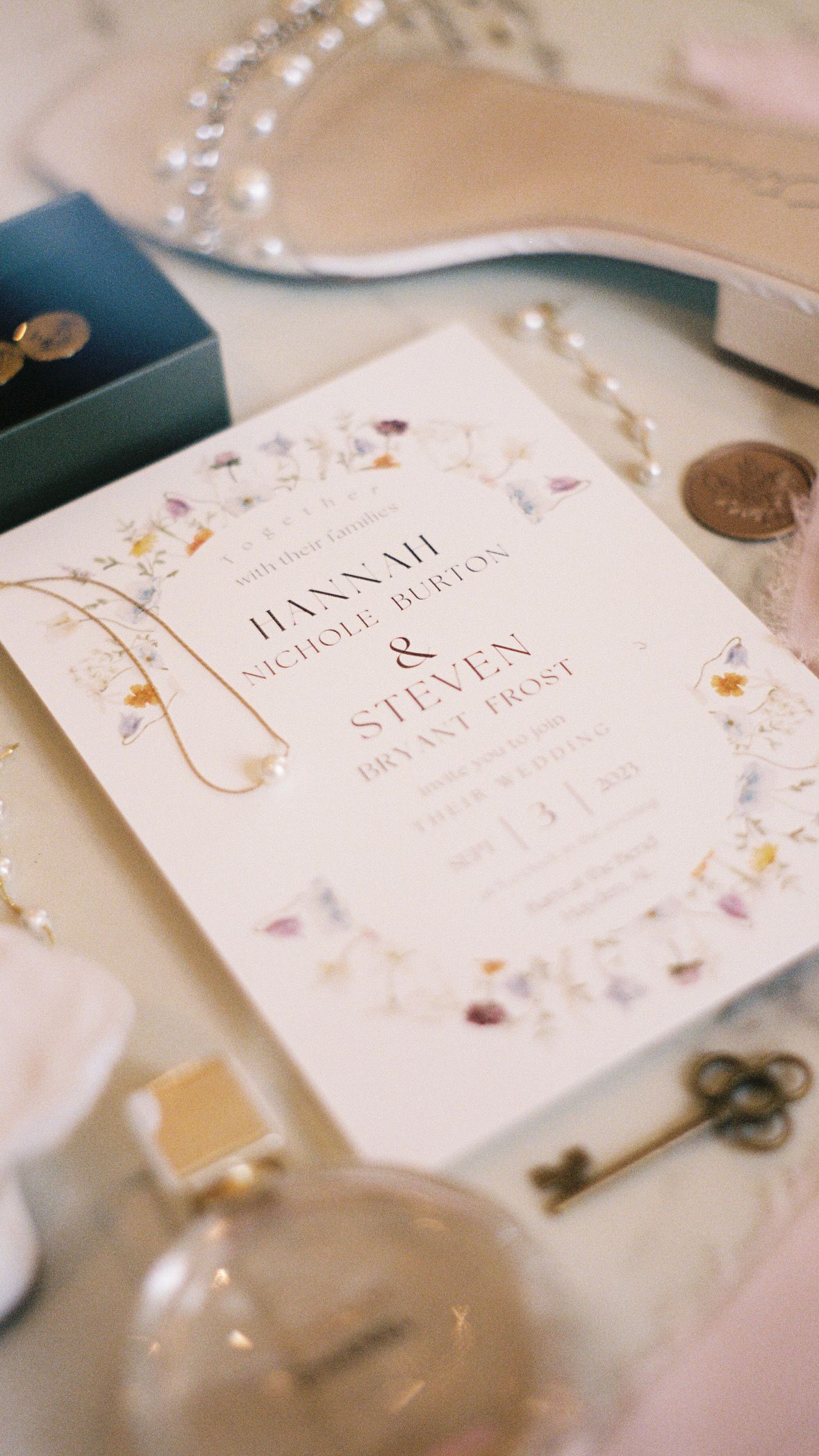 Wedding invitation cards with delicate floral designs and pearl decorations on a light background.