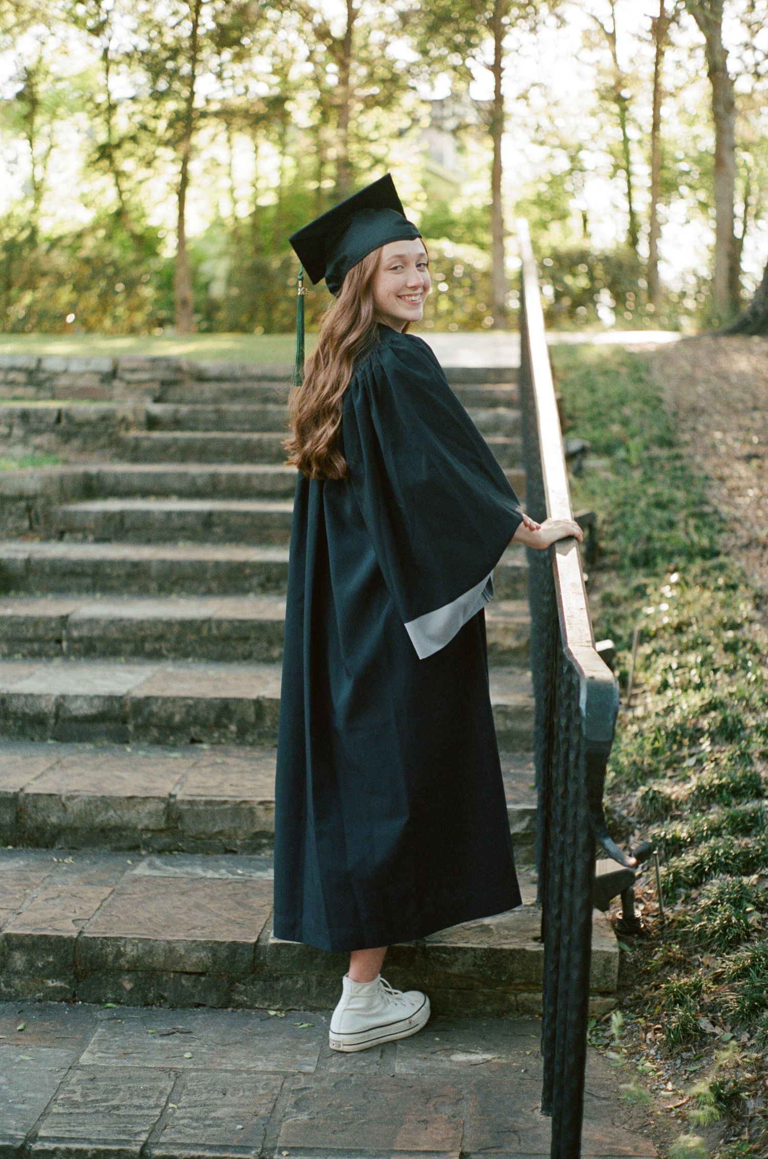 Candid graduation photos on stone steps surrounded by greenery and natural lighting.