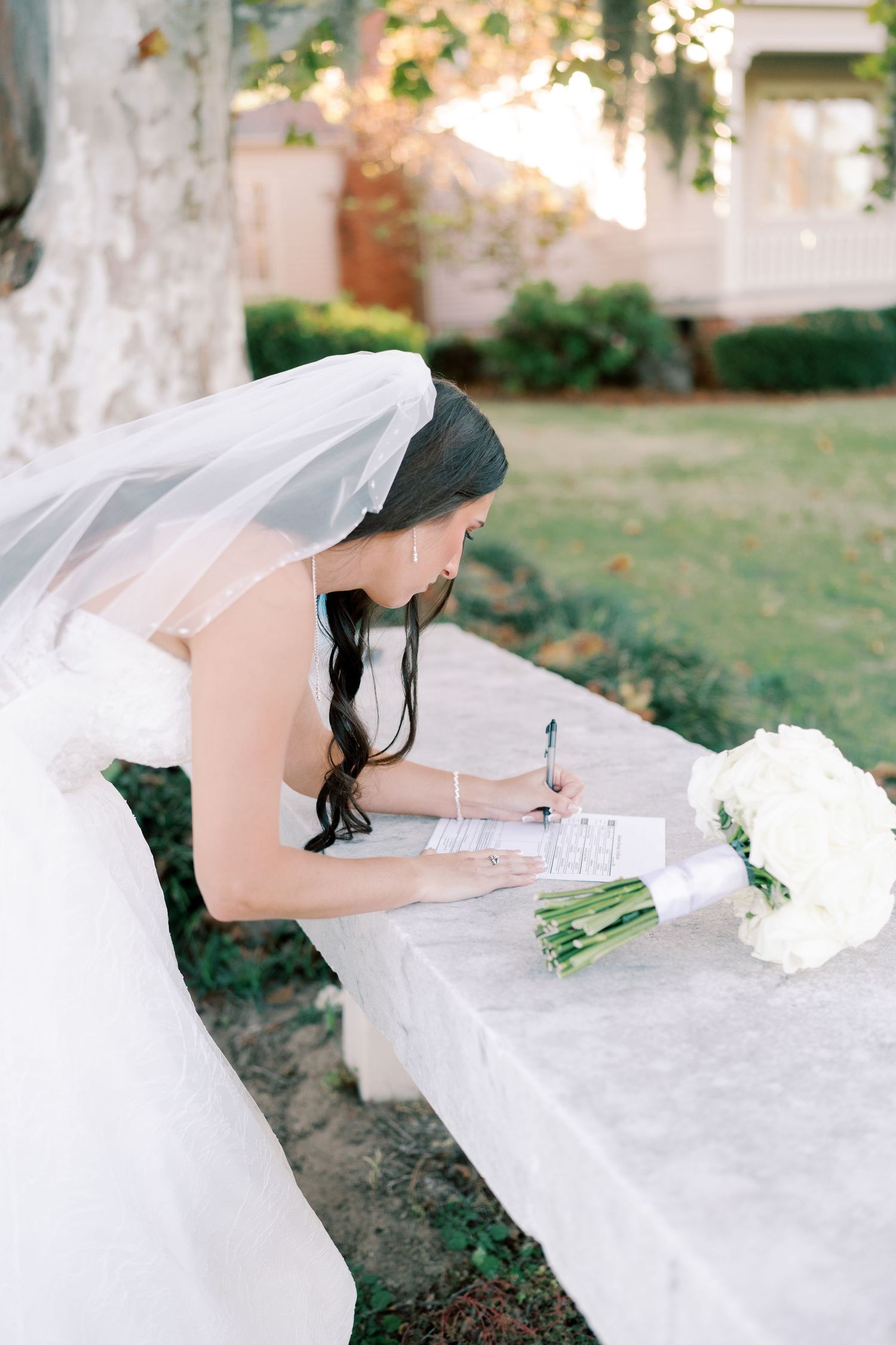 Wedding ceremony document being signed at an outdoor table with white floral decorations.