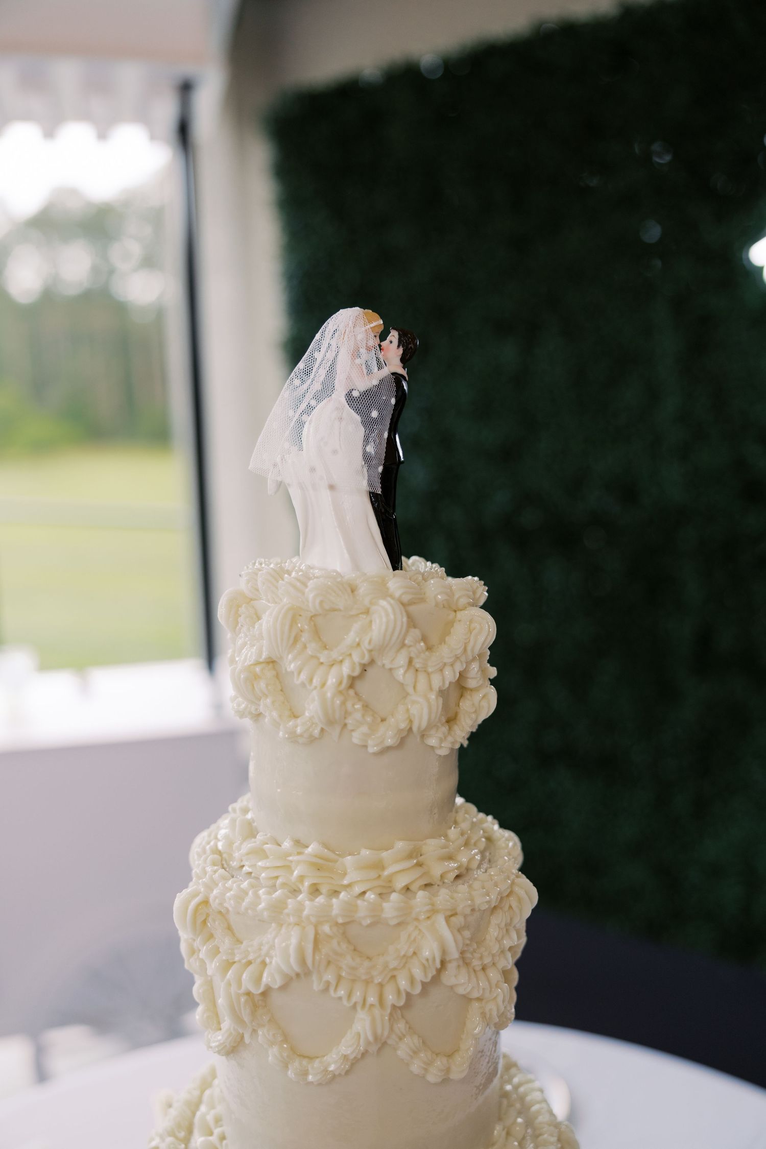 An elegant white wedding cake with delicate ruffled details and a decorative topper.