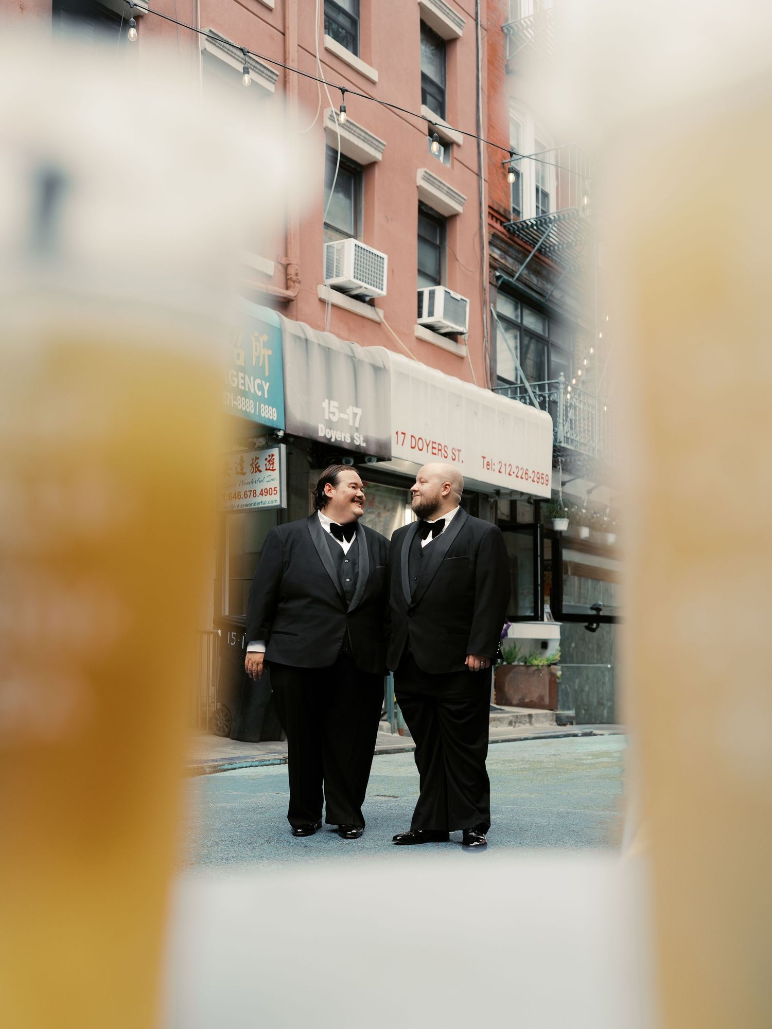 People in formal black attire walking on a city street.