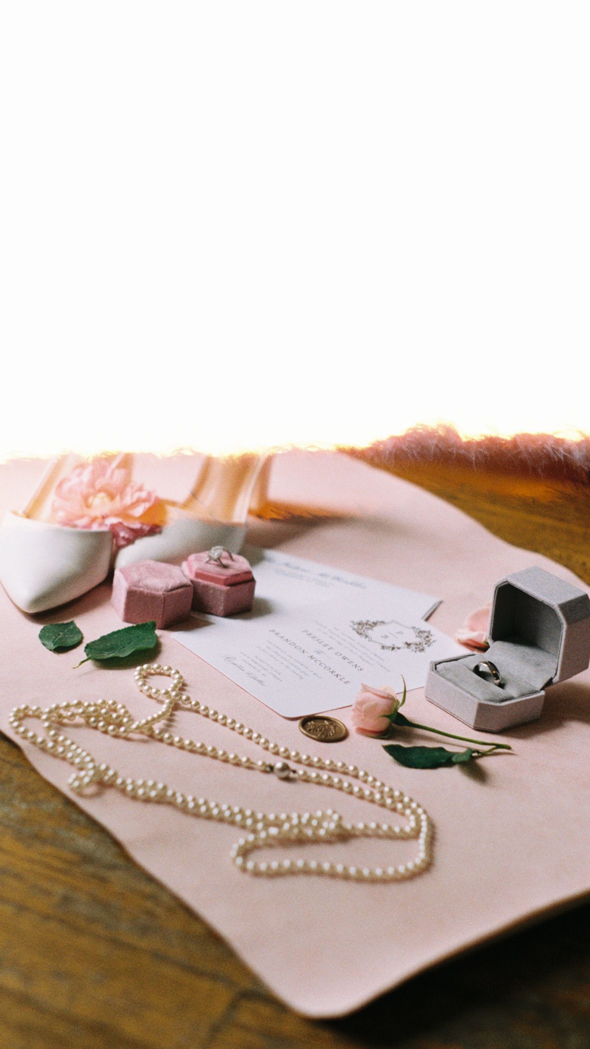 Pearl necklace and jewelry displayed on pink leather with ring box.