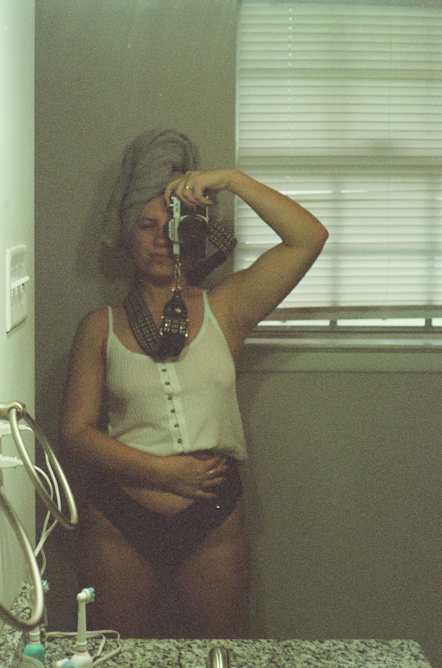 Someone taking photos in a room with venetian blinds creating a vintage film aesthetic.