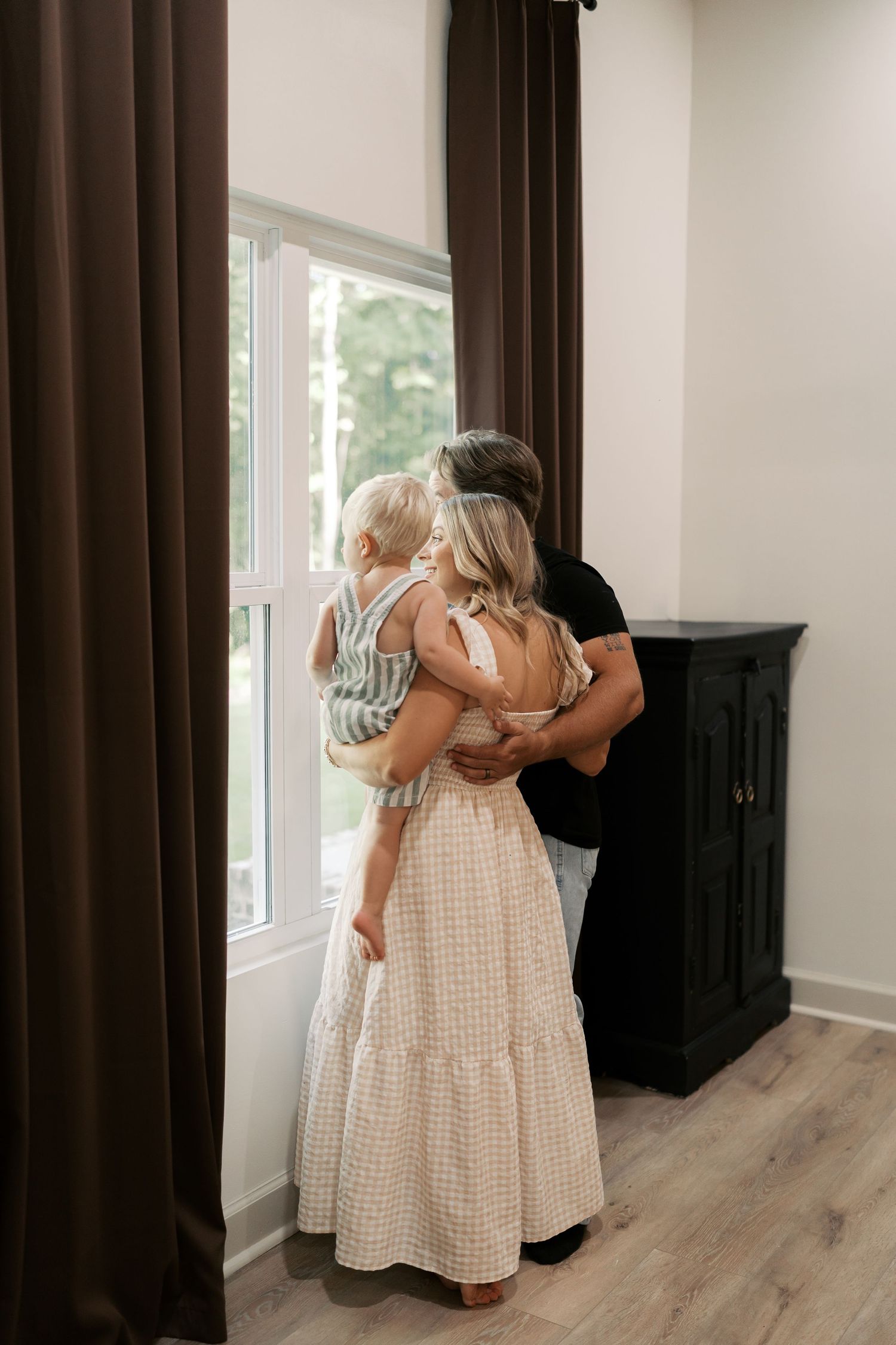 Two young children in light summer dresses embrace while playing indoors.