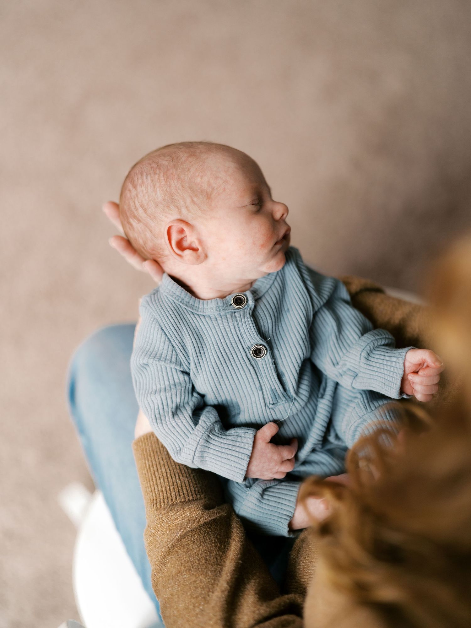 Baby wearing blue sweater held in warm embrace.