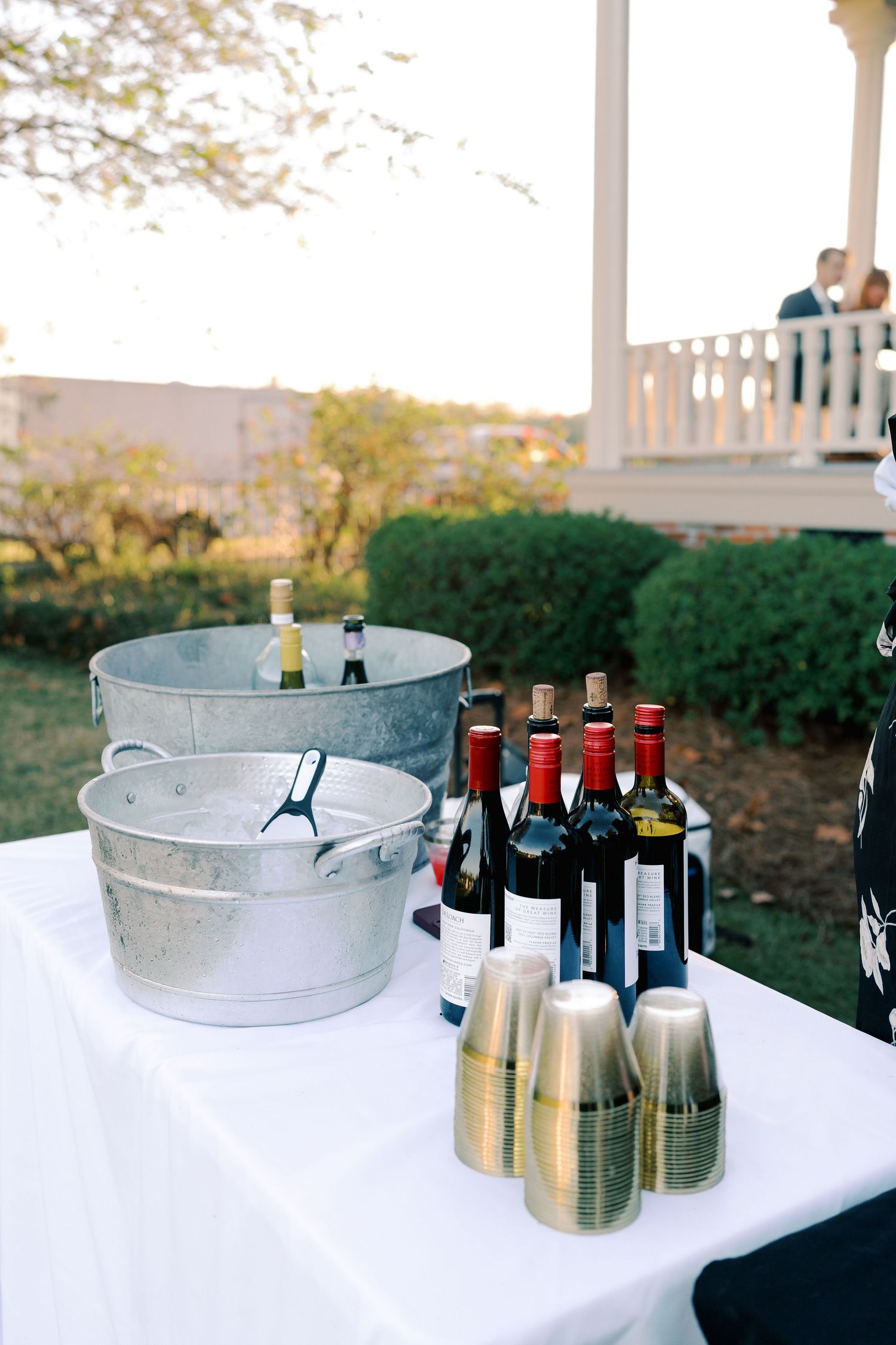 Wedding bar setup with ice buckets and wine bottles on white tablecloth.