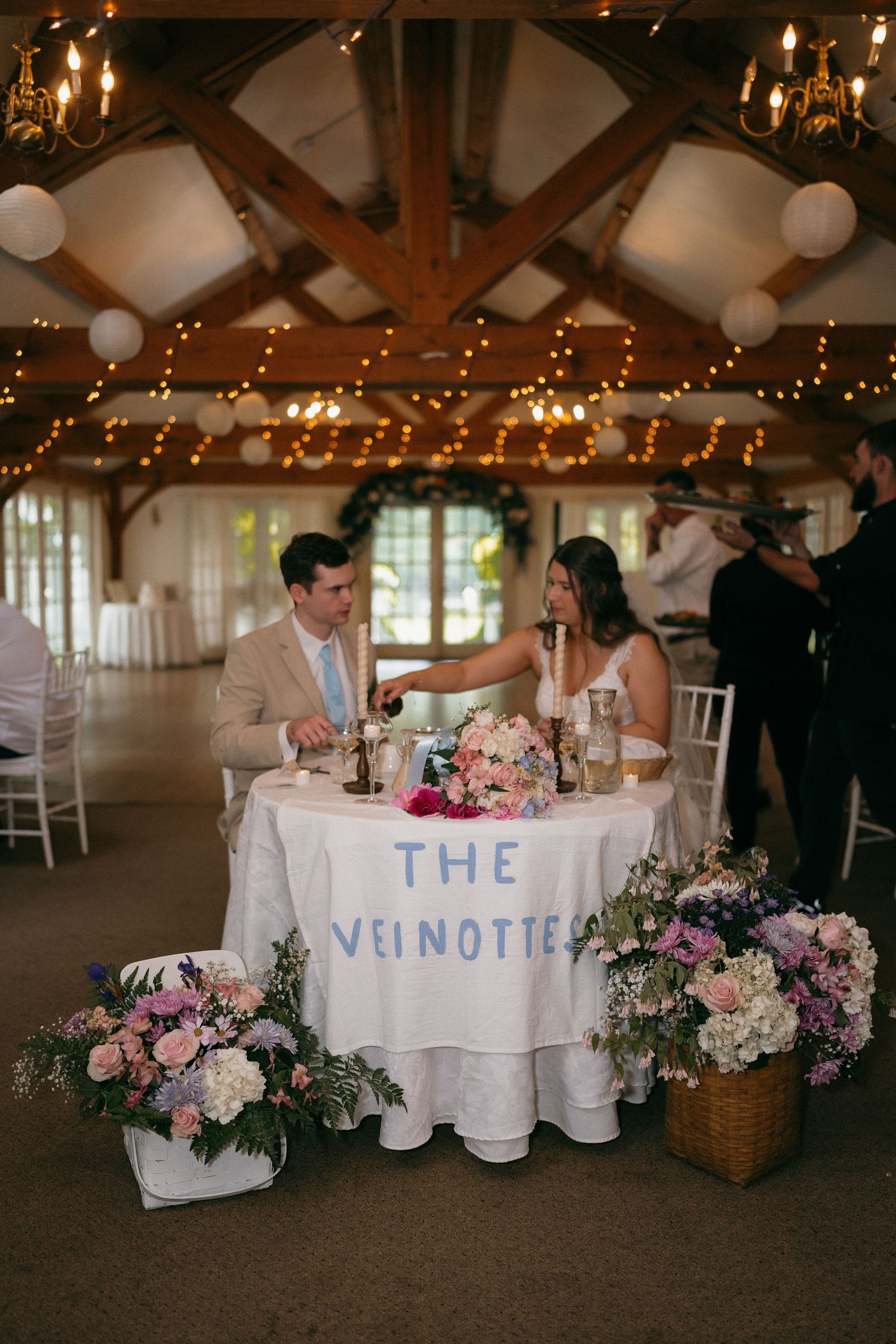 Wedding reception venue decorated with white linens, pink flowers and string lights.
